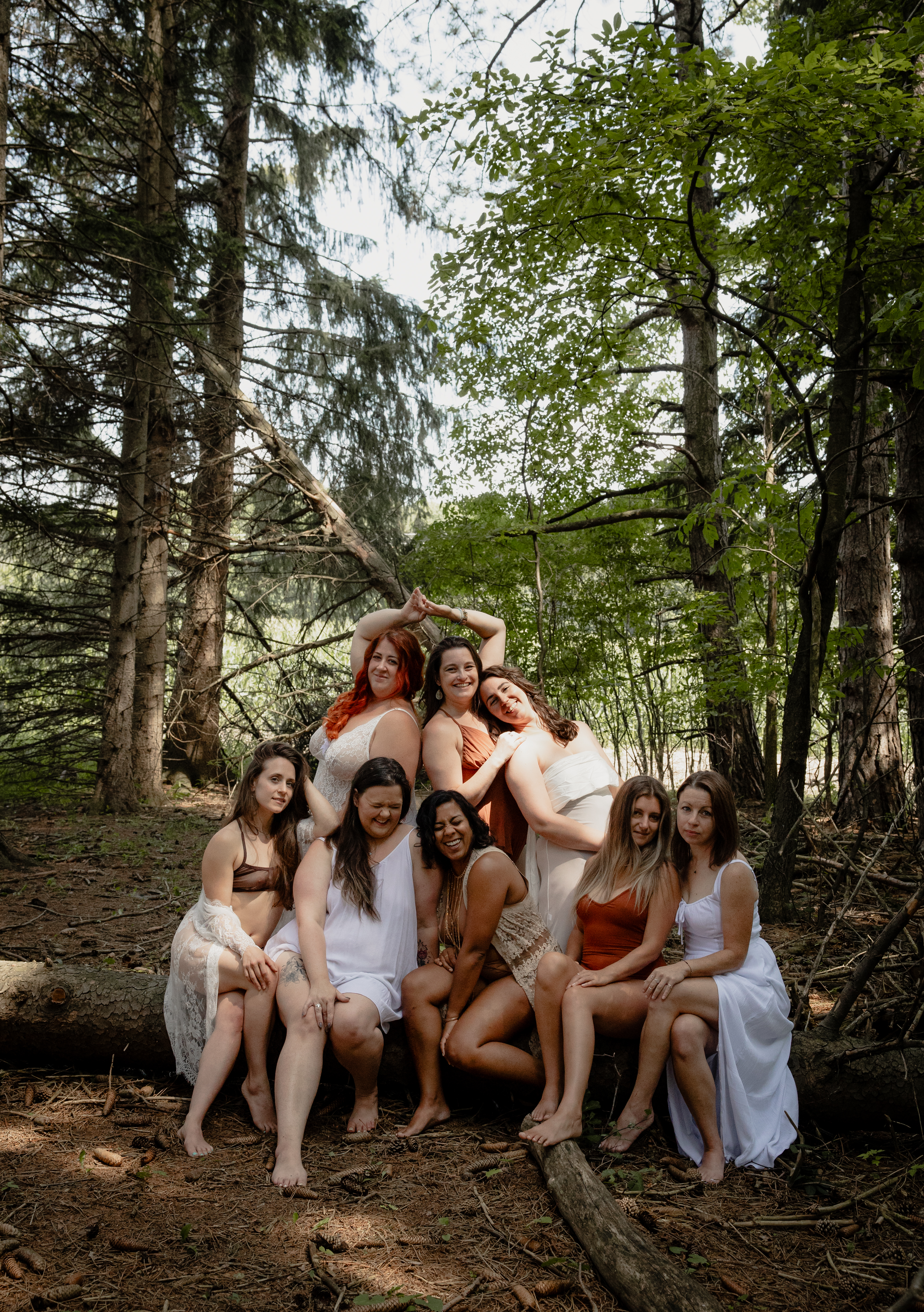 Women posing together in a forest clearing during a group empowerment boudoir session.