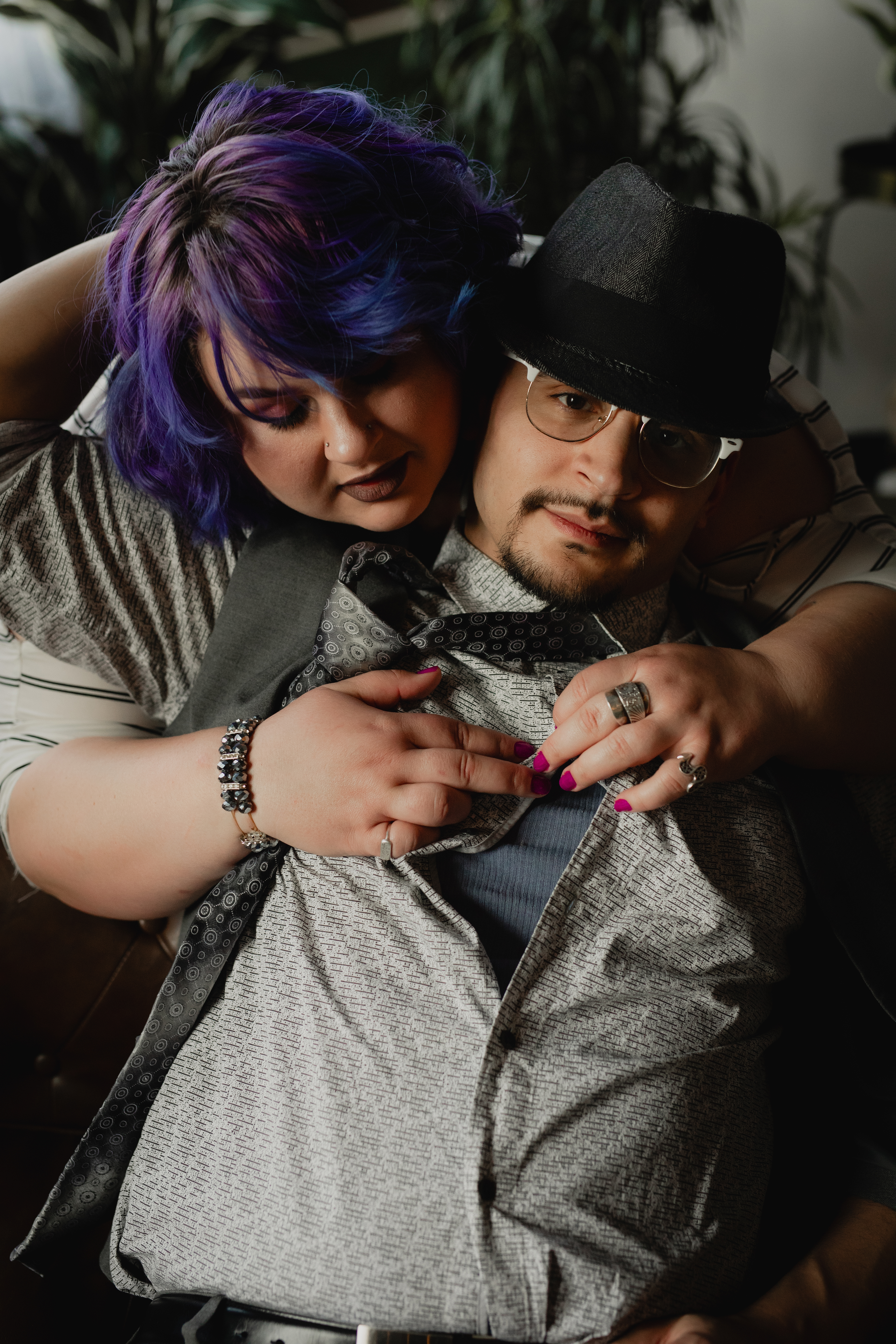 Intimate boudoir photo of a couple cuddling on a couch in a cozy indoor setting.