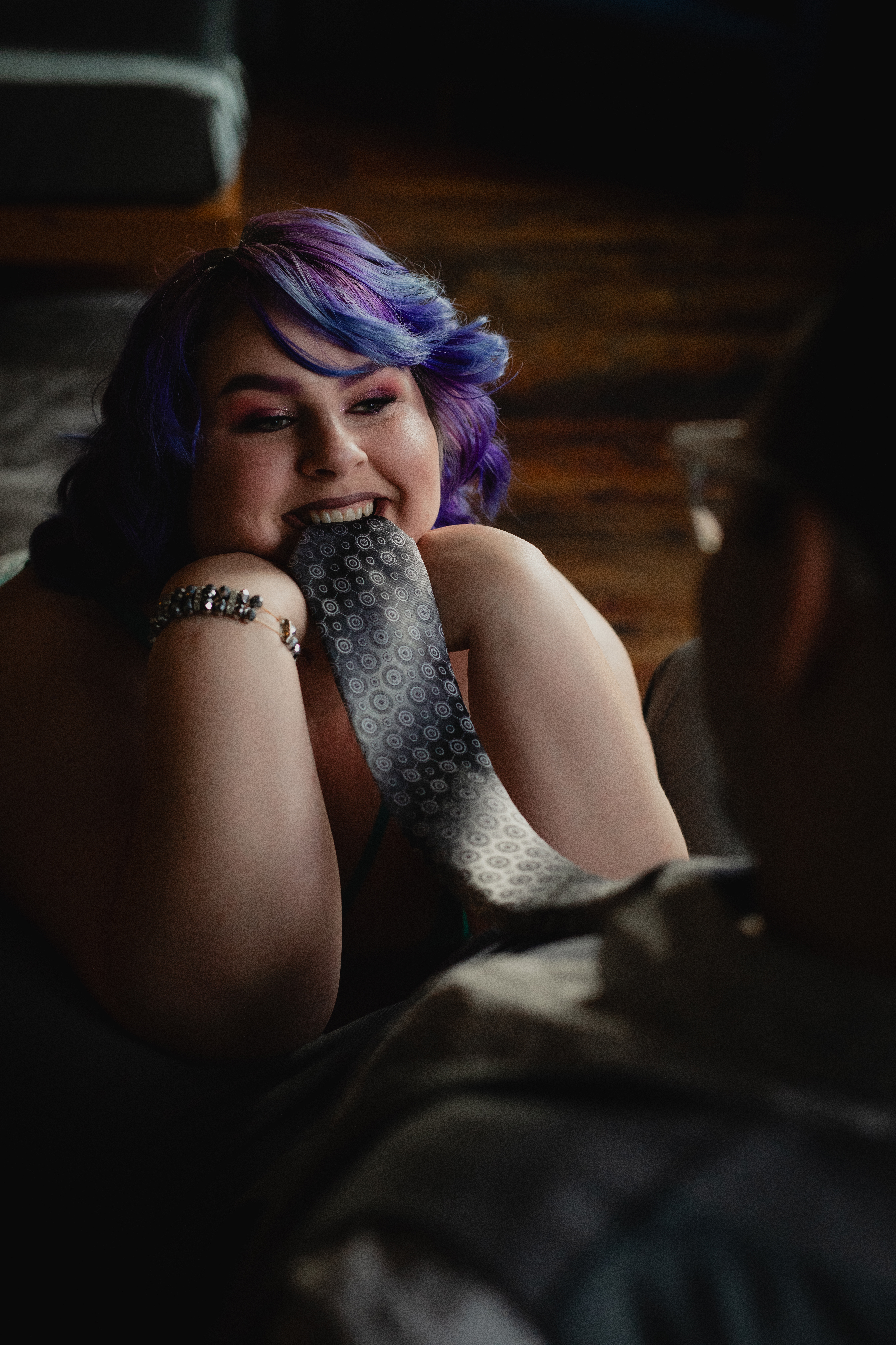 Close-up boudoir portrait of a woman with colorful hair posing in soft lighting.