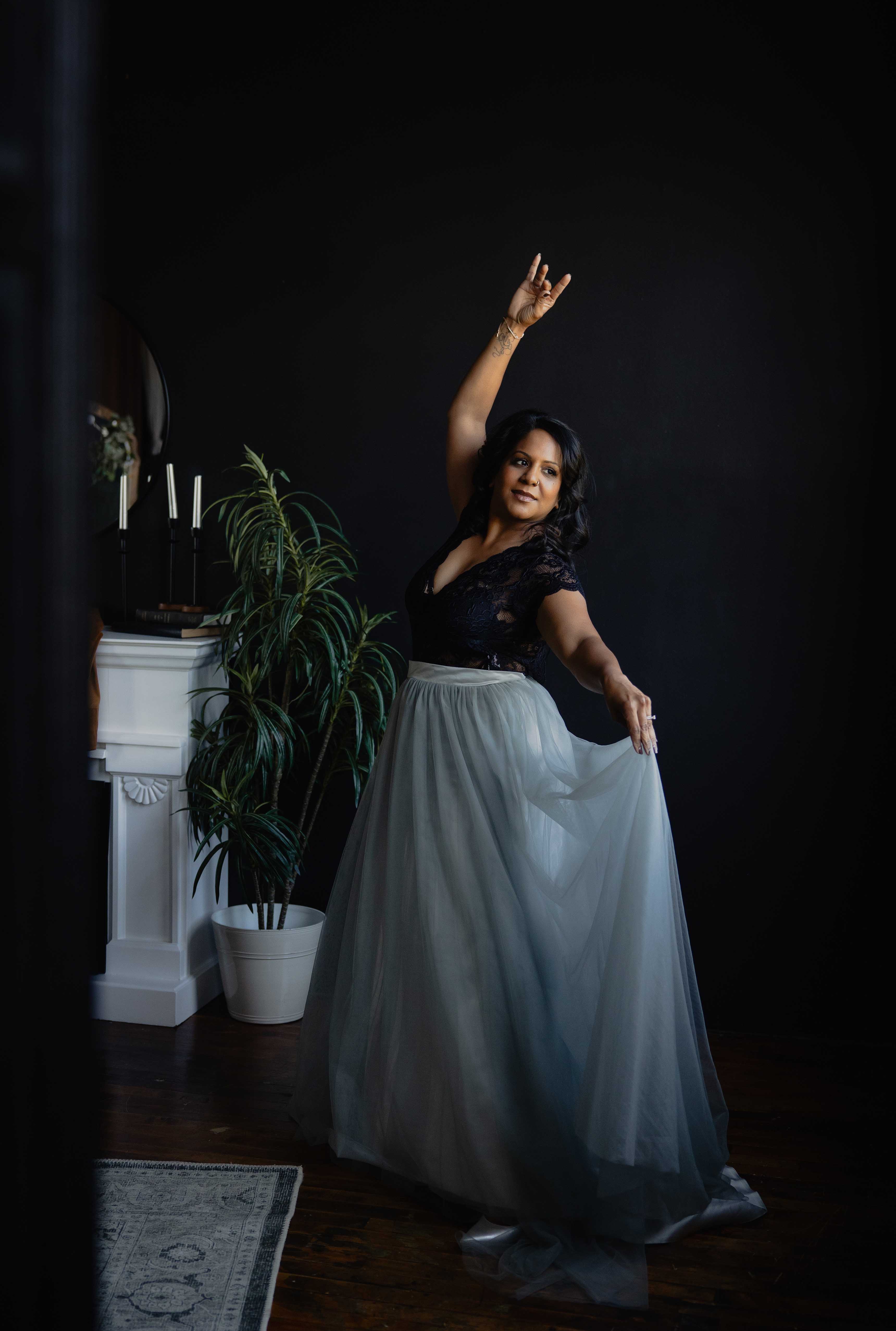 Empowering boudoir photography of a woman posing confidently in a flowing skirt in a studio setting.