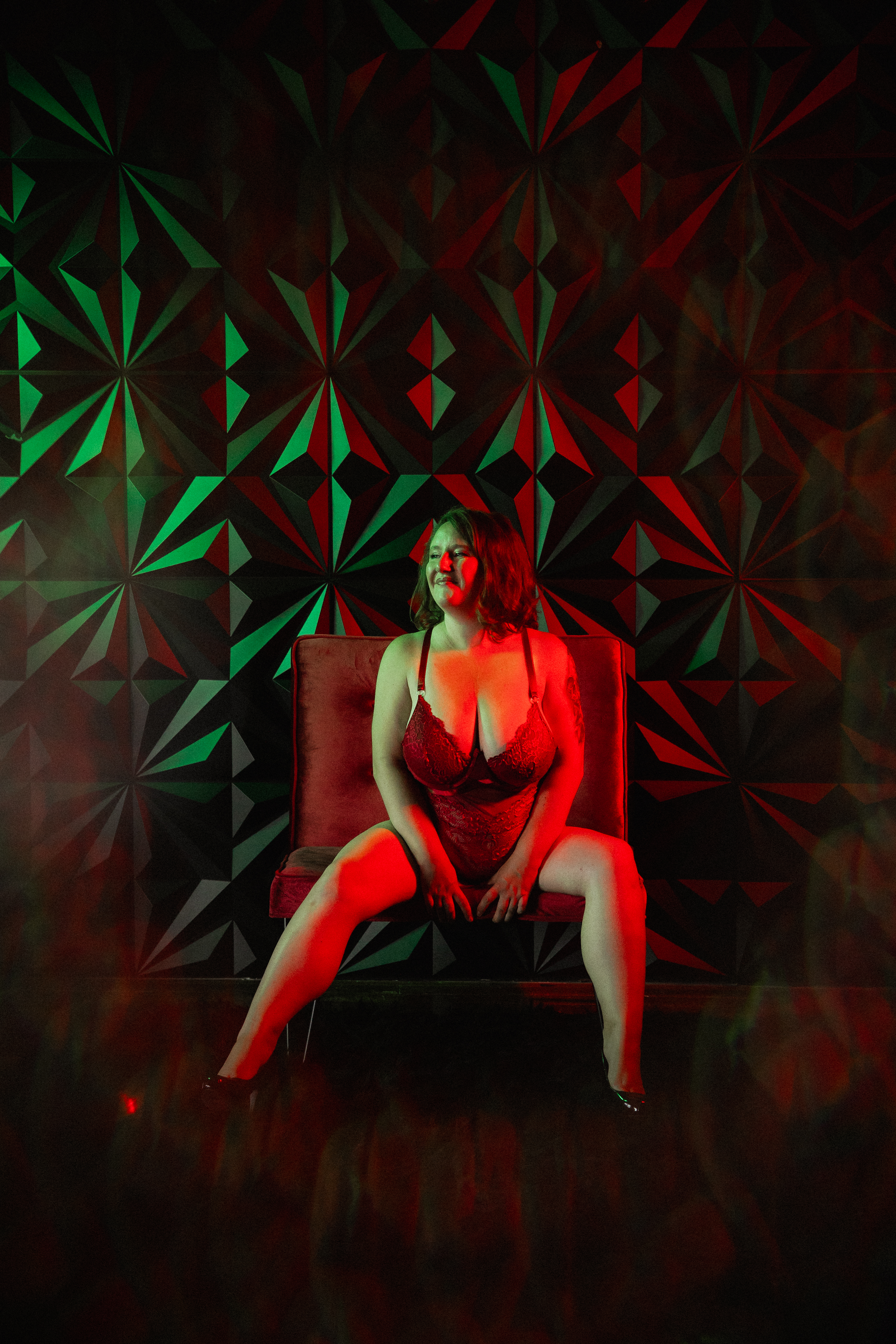 Artistic boudoir photo of a woman in red lighting with geometric background for a bold, editorial look.