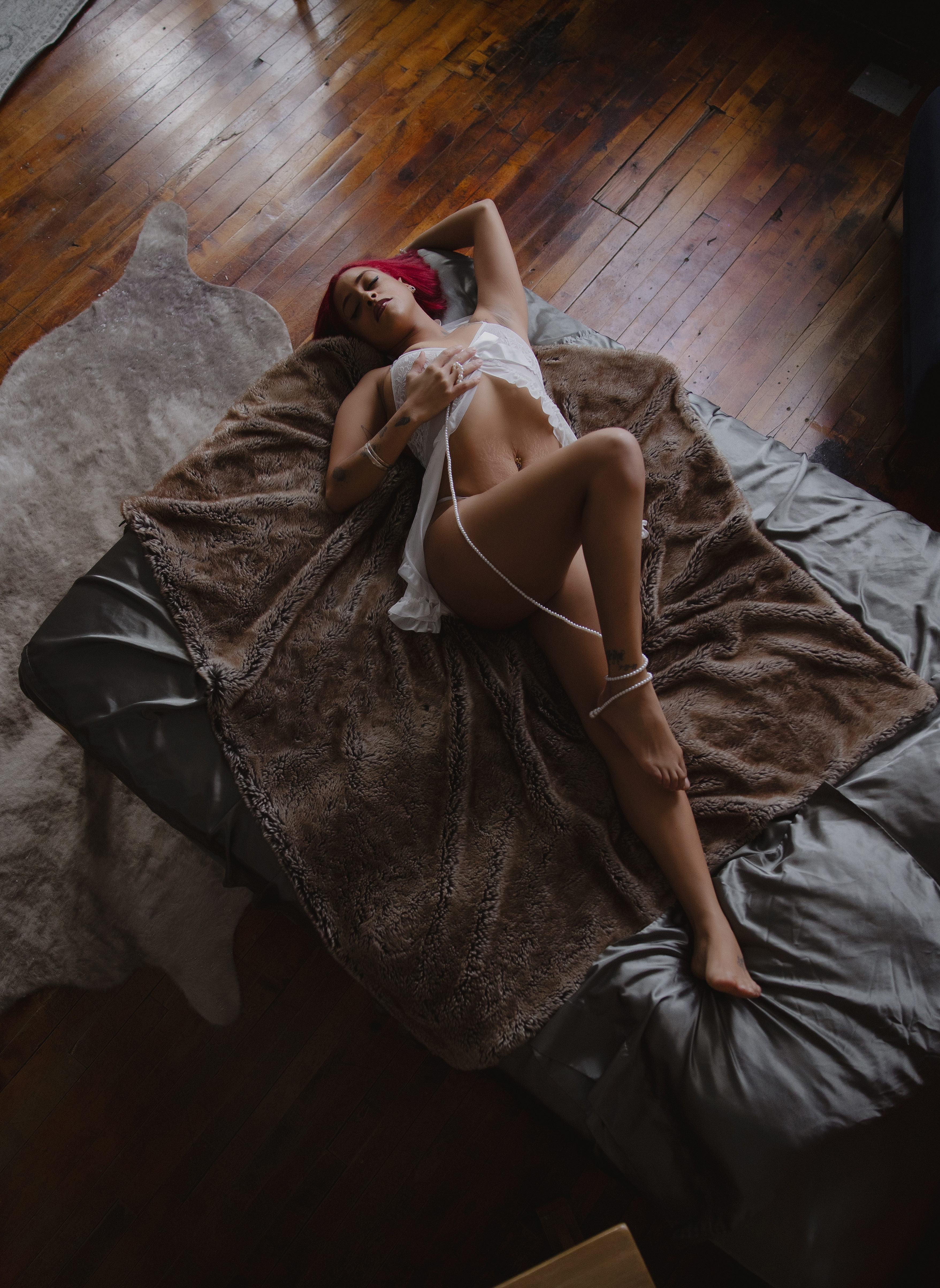 Woman reclining on a bed in white lingerie during a moody boudoir photography session. Woman reclining on a bed in white lingerie during a moody boudoir photography session.