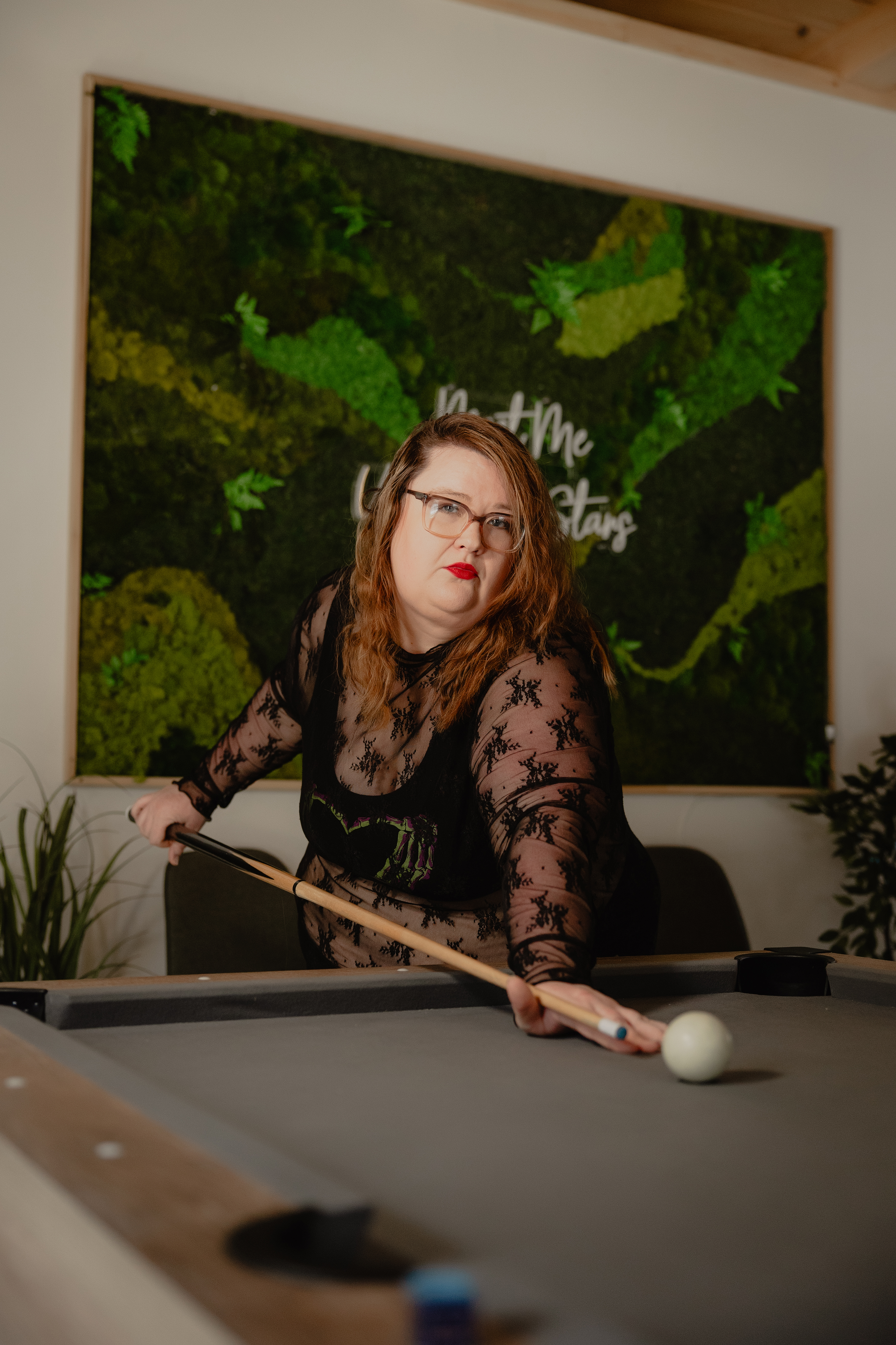 Woman posing outdoors near greenery in a natural light portrait.