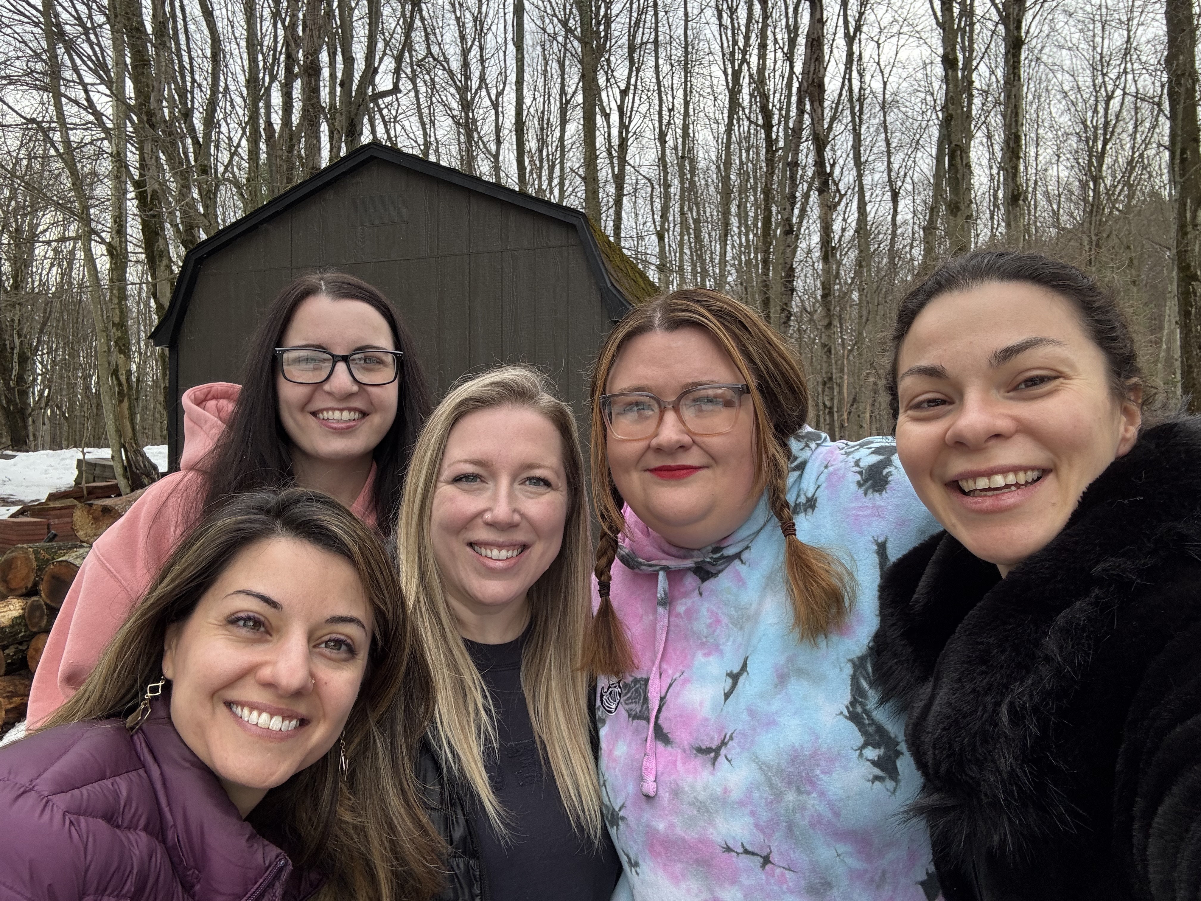Group of women smiling together outdoors in a forest setting.