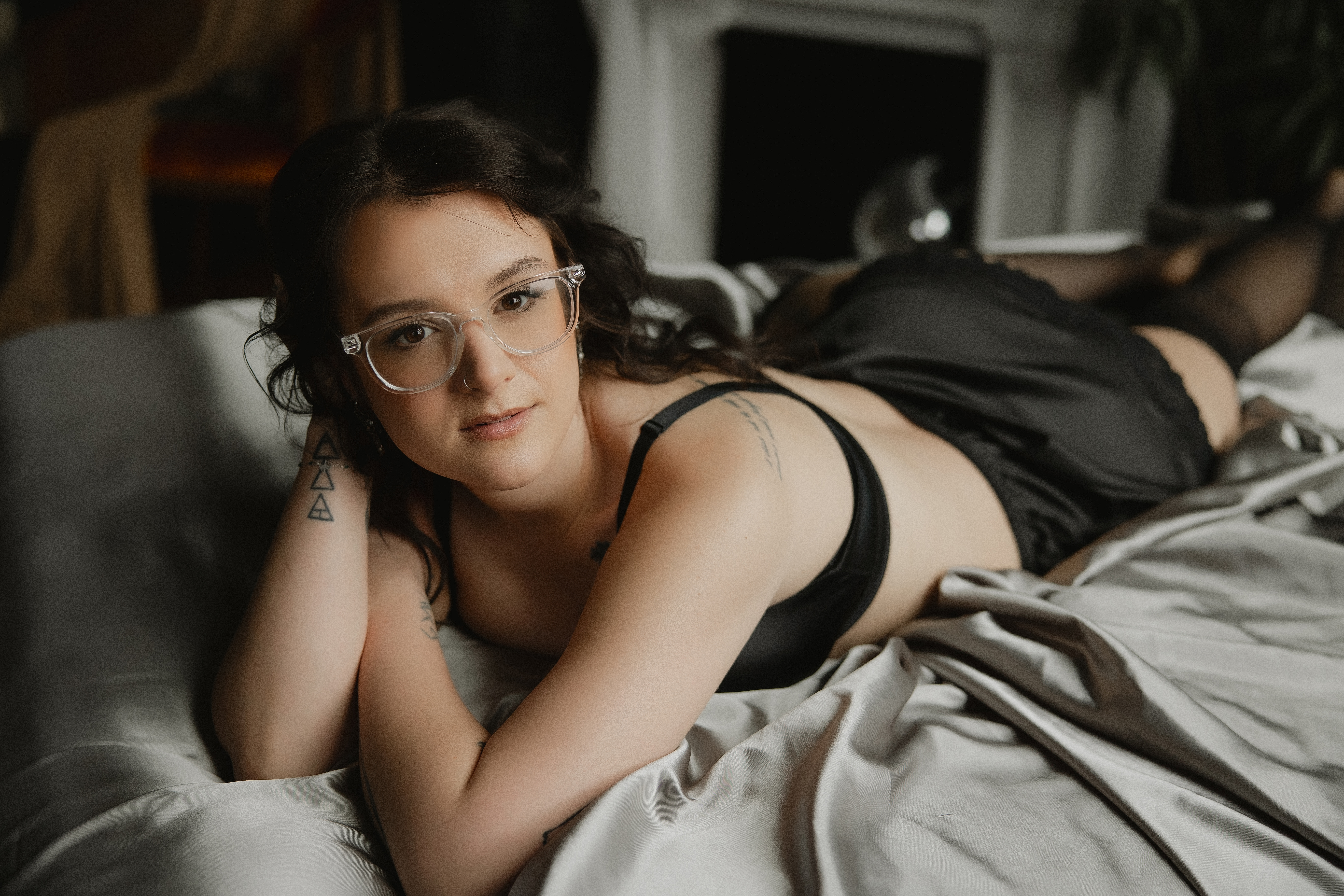 close-up of woman in glasses lying on bed, intimate boudoir portrait