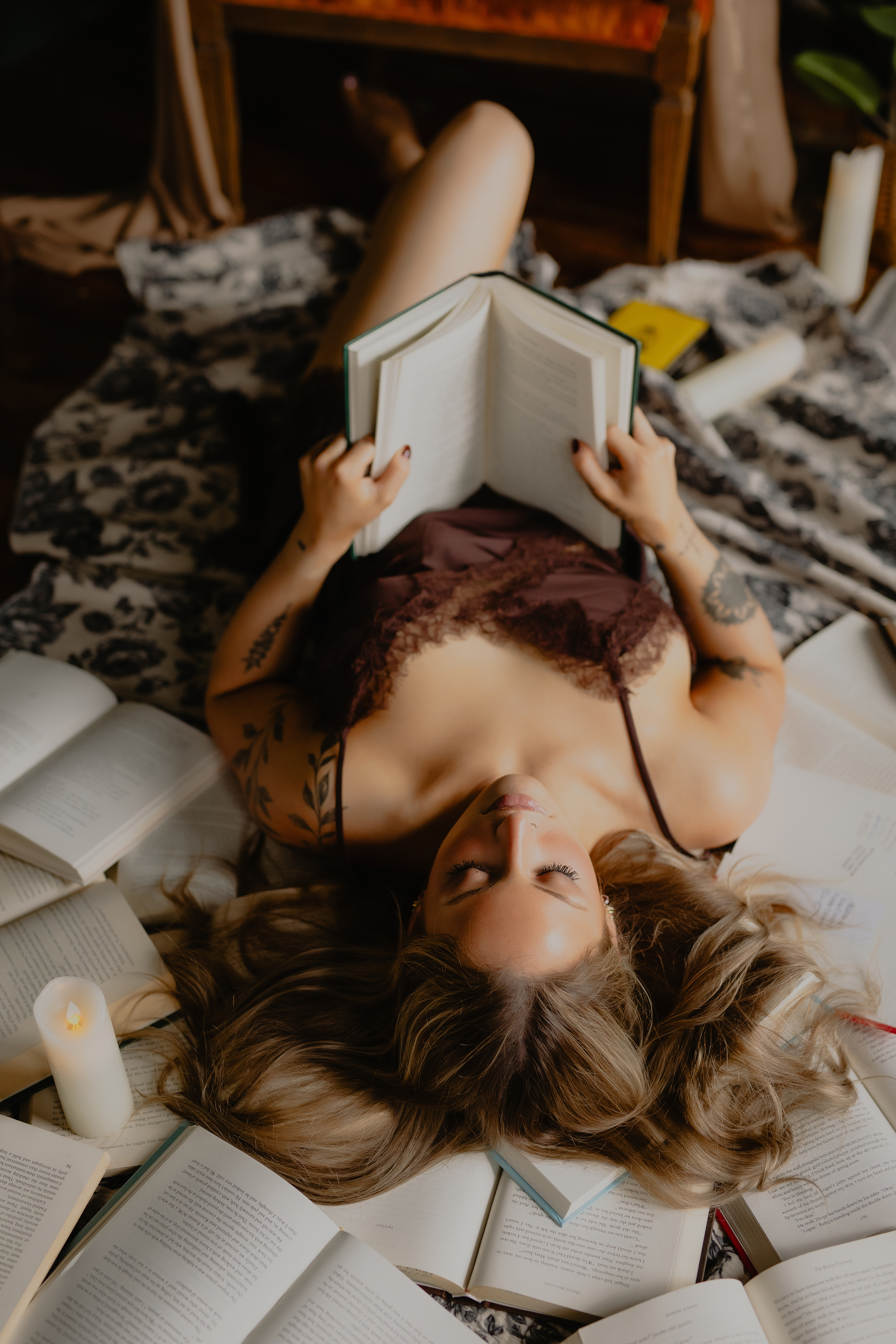girl laying with books and holding a book