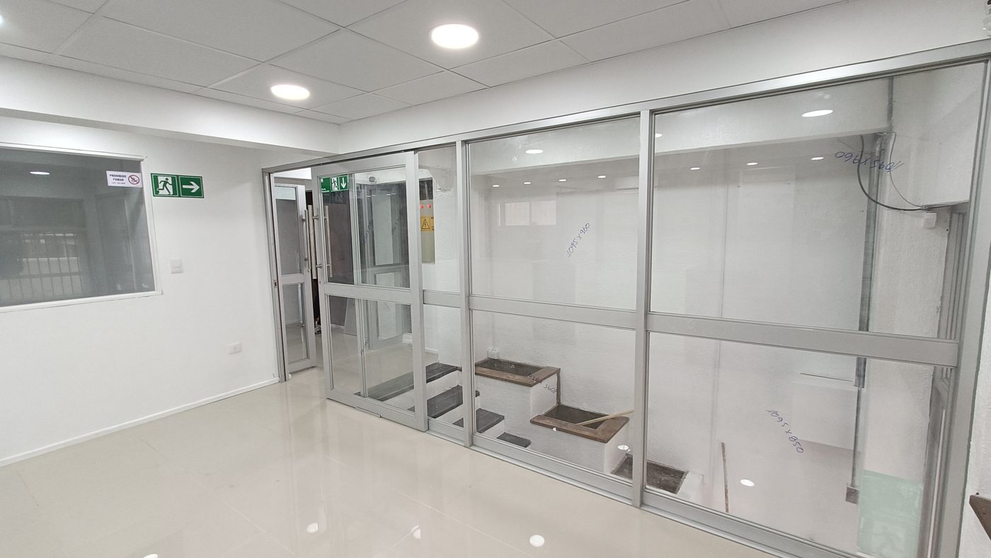 Tabiquería de vidrio y aluminio con puerta de acceso en el local Red Farma