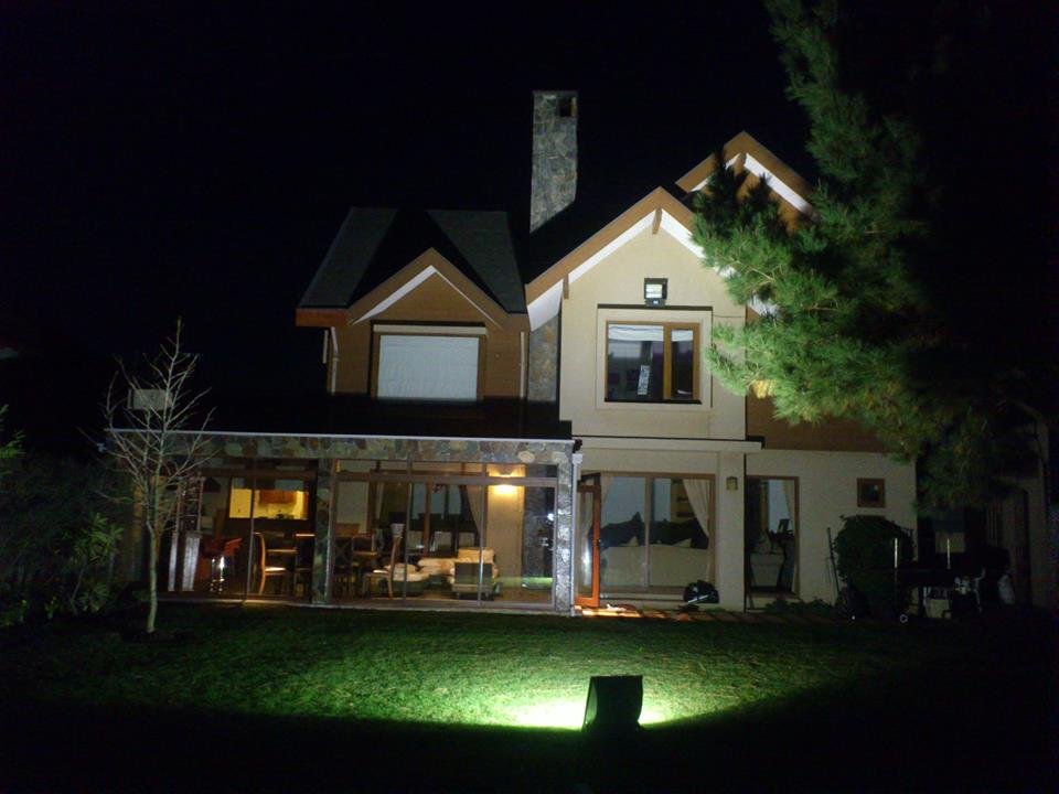 Casa en Fundo El Venado de noche, con la ampliación tipo quincho en piedra y vidrio integrada al primer piso