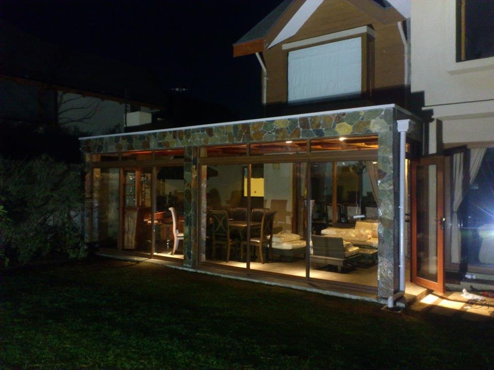 Quincho en Fundo El Venado iluminado de noche, con pilares de piedra laja y ventanales con termopanel