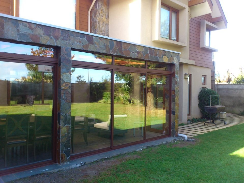 Quincho en Fundo El Venado de día, con marcos de piedra laja y ventanales con termopanel hacia el jardín