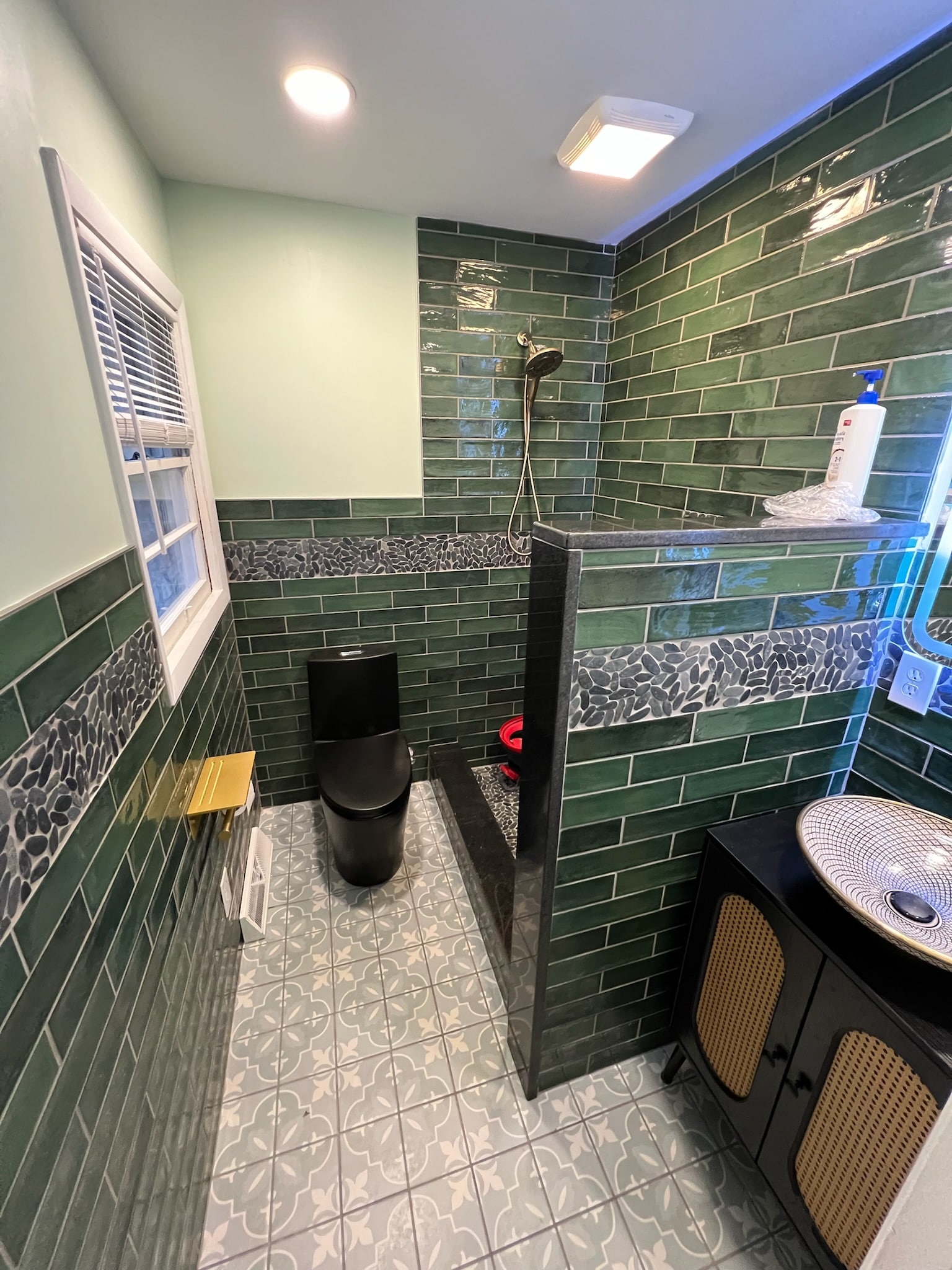 a bathroom with green tile walls and a toilet