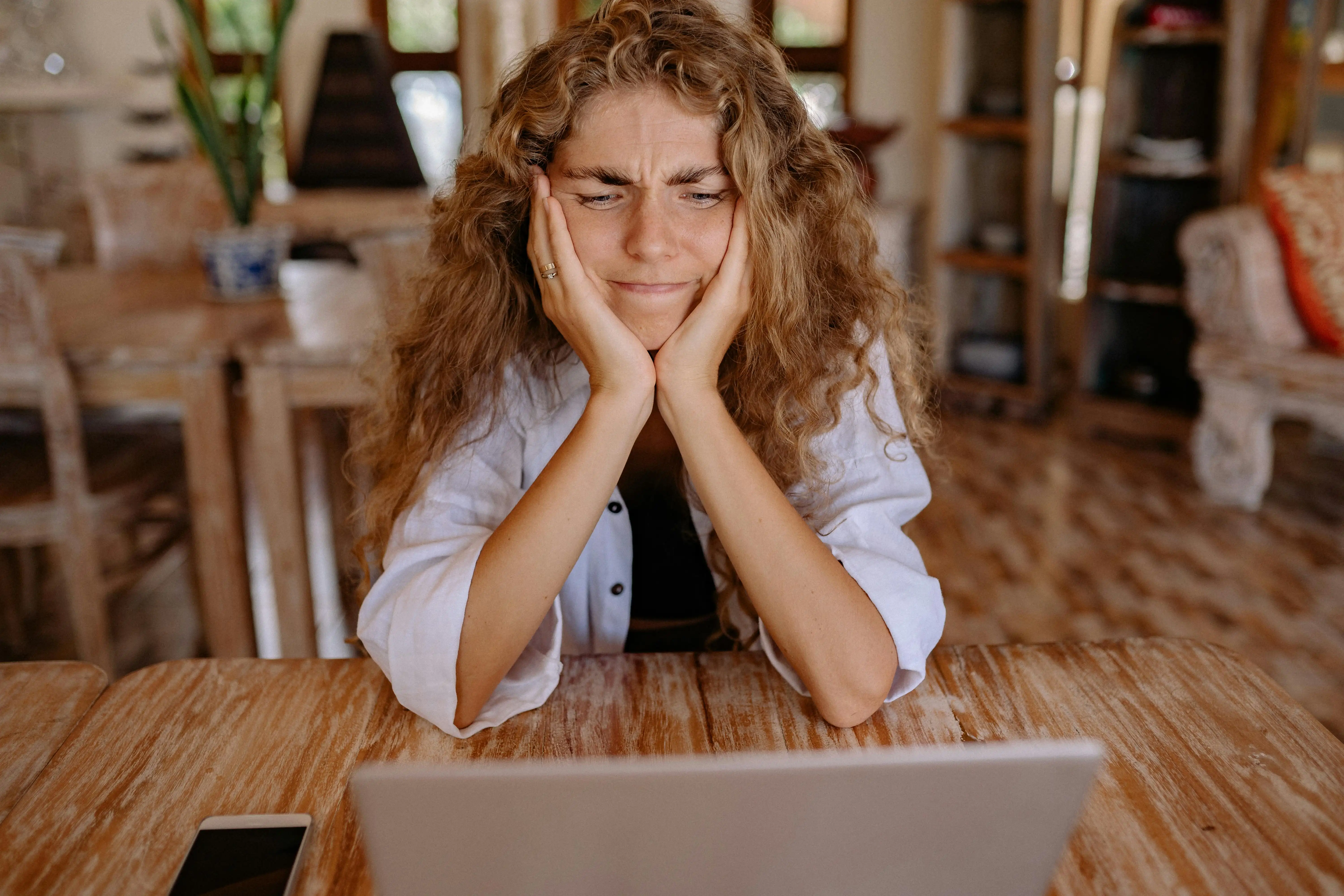 Female entrepreneur pausing at her desk before publishing a live launch offer, representing the visibility wound that causes women business owners to shrink before going visible