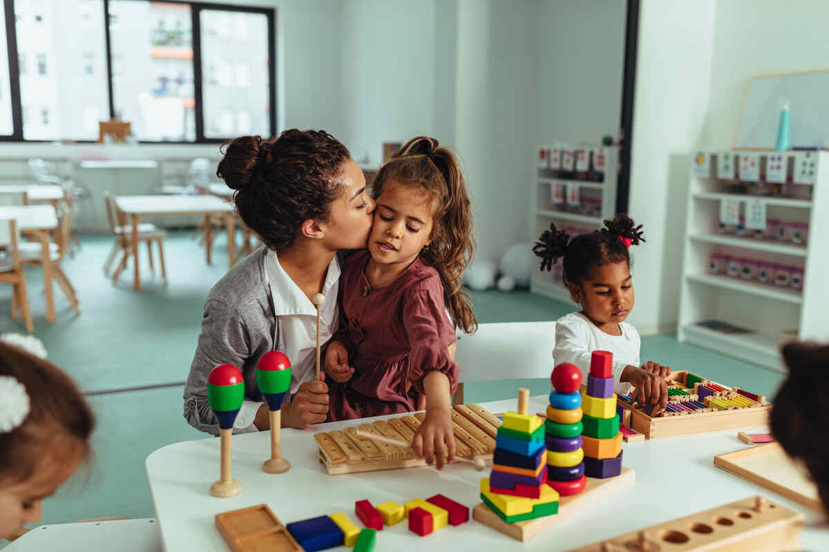An early childhood educator at Sugar N Spice Day Care soothing a preschool child in a cozy classroom reading nook