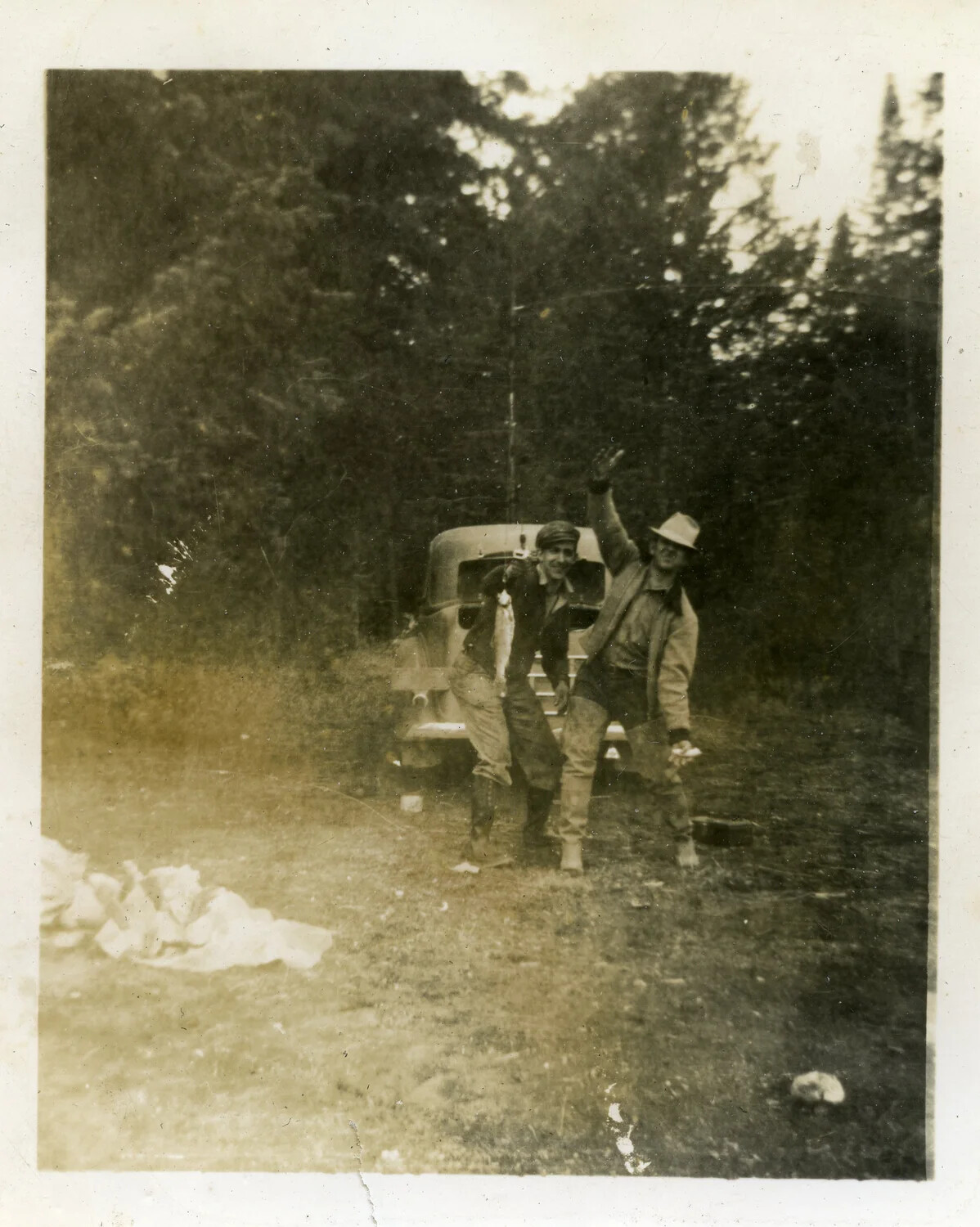 Two Men with Fishing Catch Beside Automobile, Wooded Clearing (Pre-War Family Snapshot)