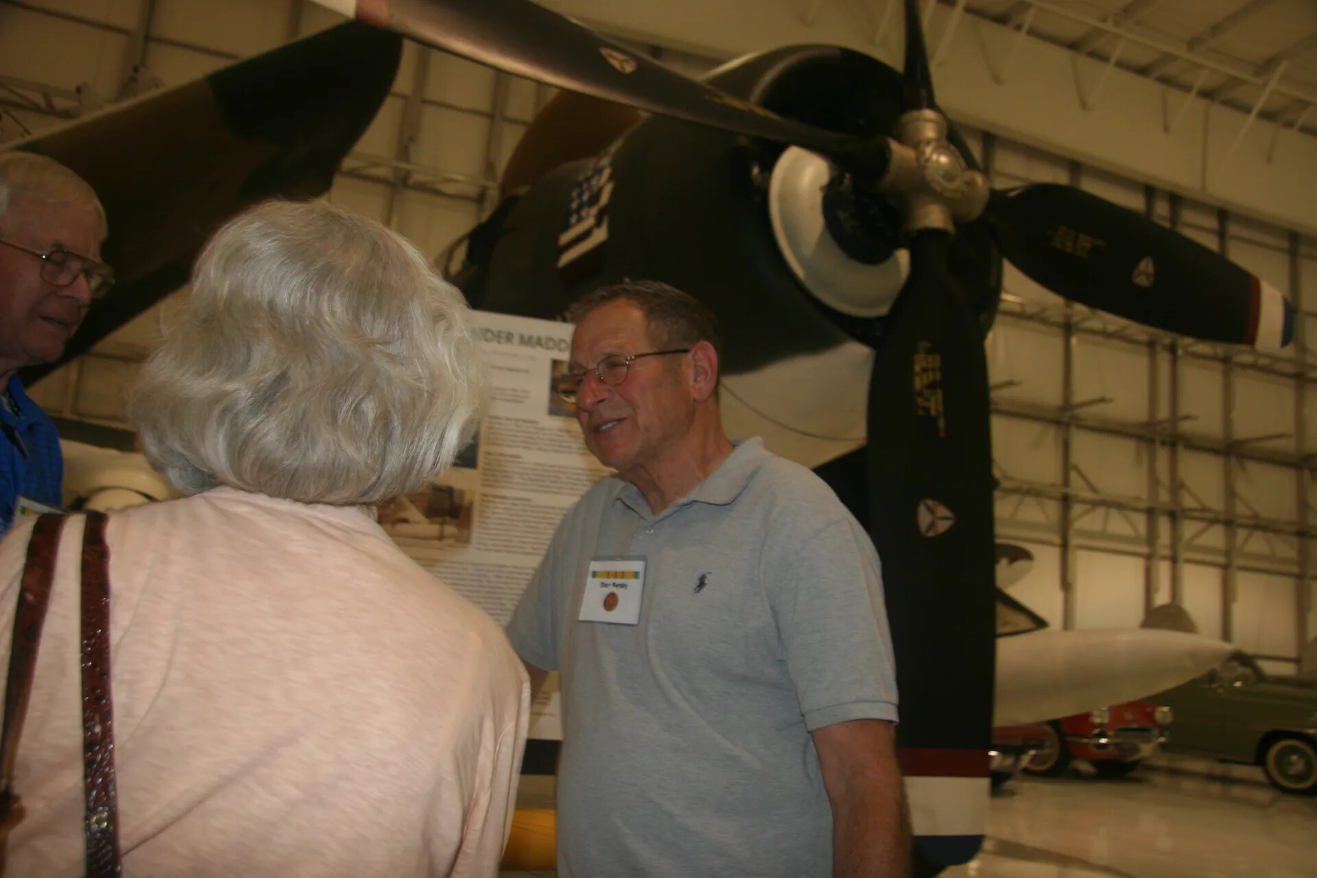 Museum Visitors Conversing Beneath Vintage Military Aircraft Nose, Aviation Museum