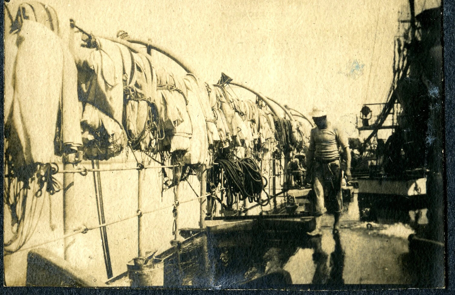 Sailor Walking Wet Deck Past Stowed Hammocks, USS Columbia, circa 1898-1907