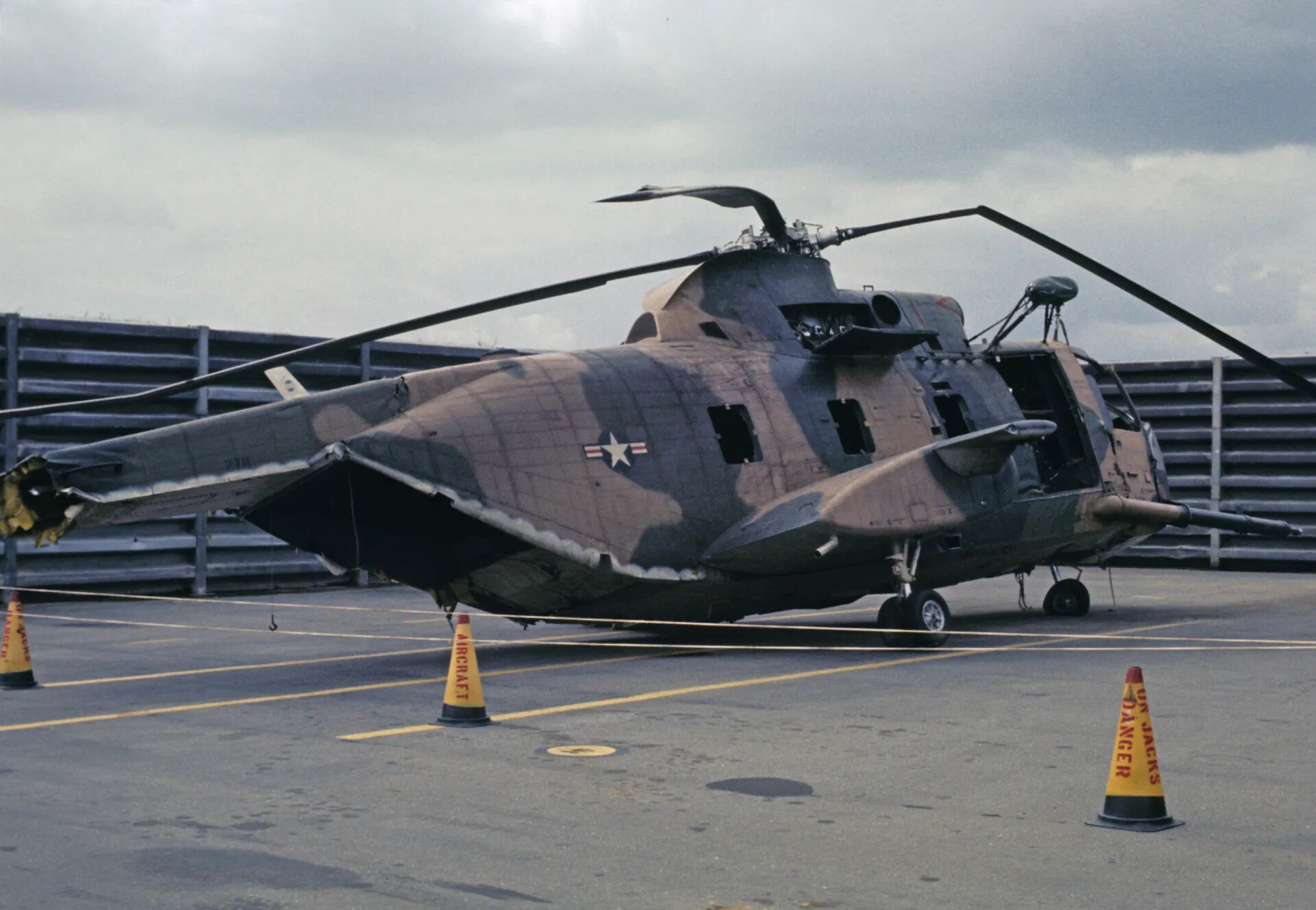 Battle- or Crash-Damaged Sikorsky-Type Helicopter on Ship's Deck, Southeast Asia Camouflage