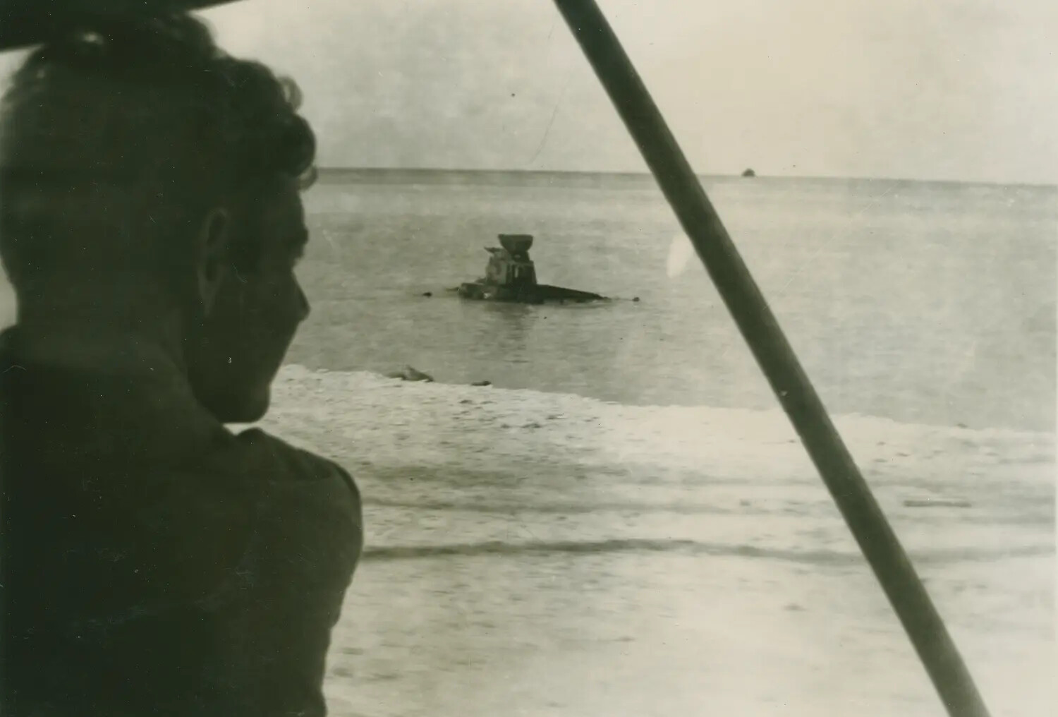 Serviceman Observing Wrecked Amphibious Vehicle in Lagoon, WWII Pacific Theater