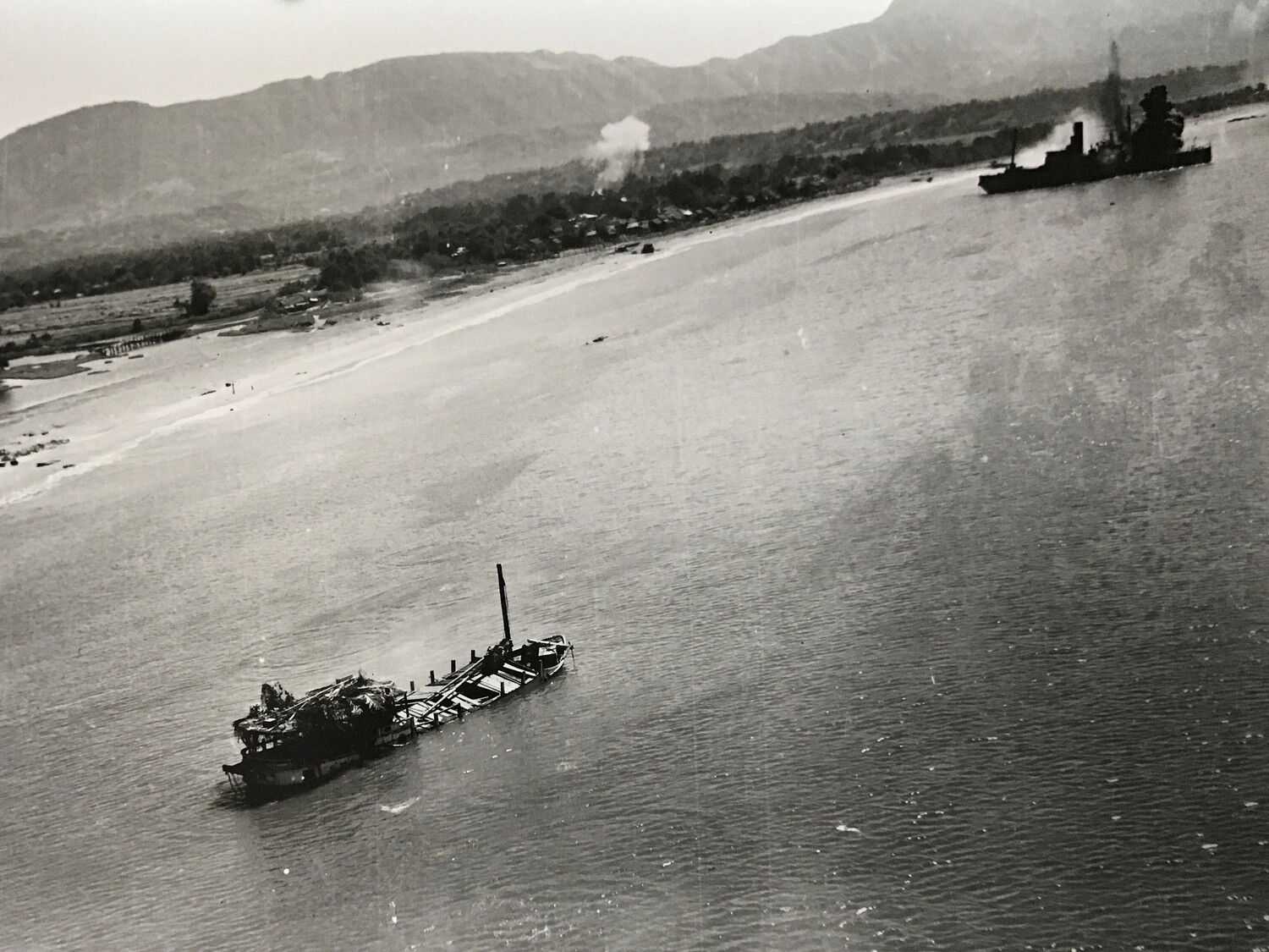 Aerial View of a Wrecked Coastal Vessel and U.S. Navy Ship Off a Pacific Beachhead, WWII