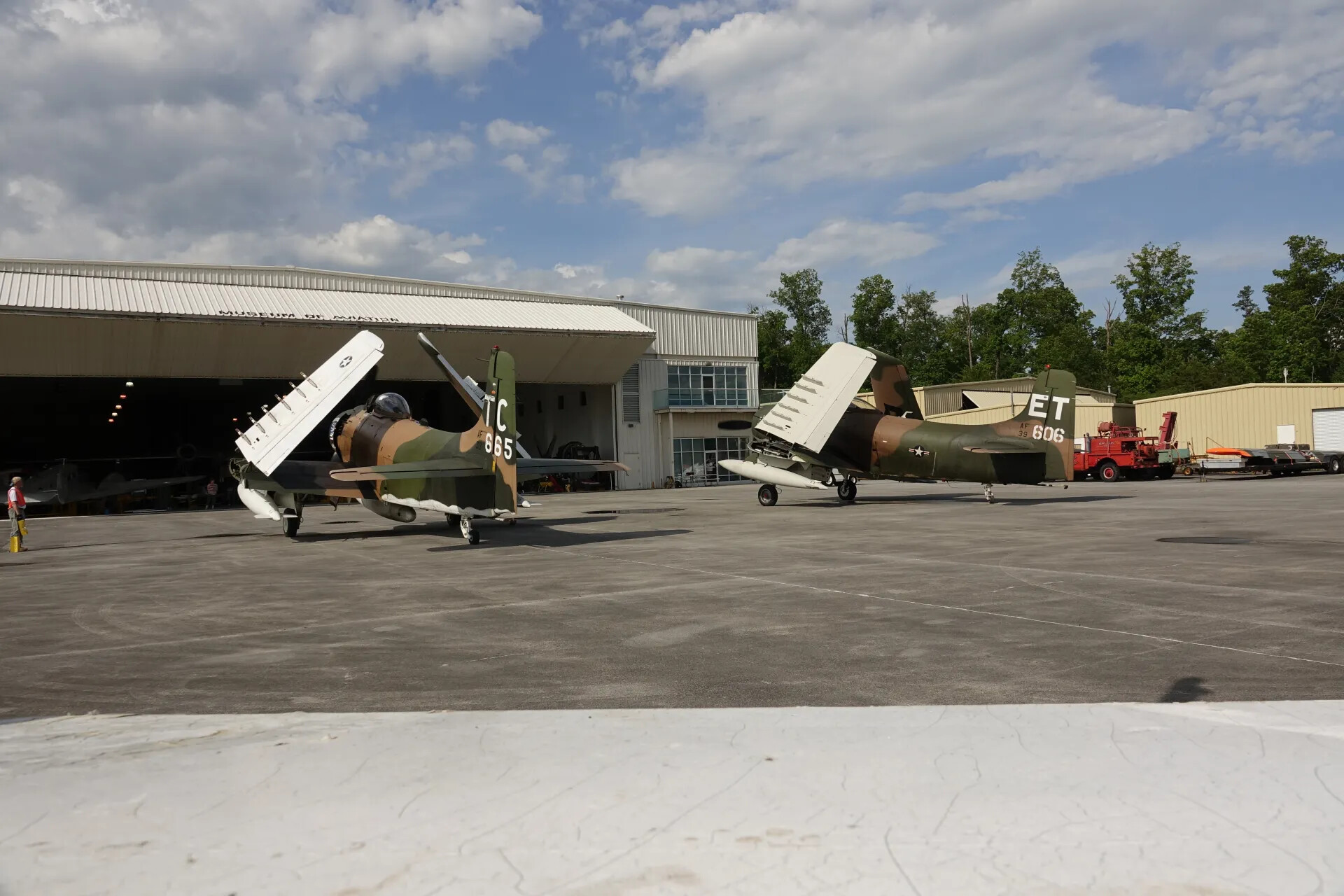 Two Douglas A-1 Skyraiders, Wings Folded, Parked at Museum Hangar with Ground Crew