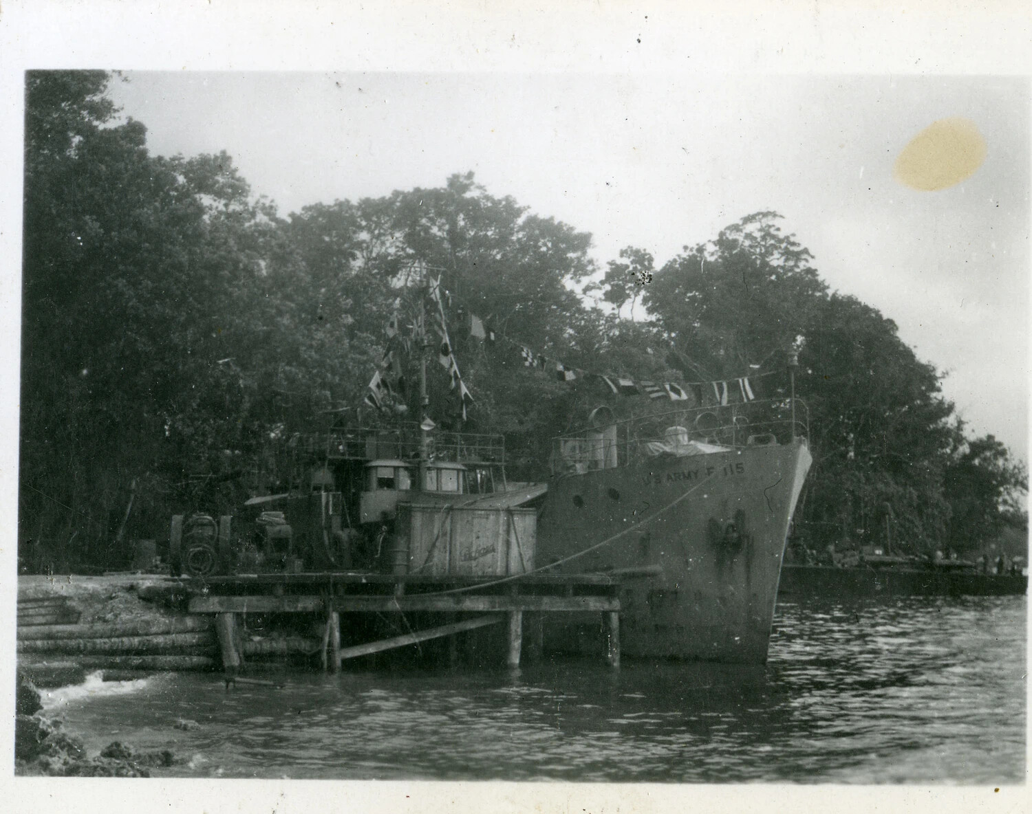 U.S. Army Freight and Supply Vessel F-115 Dressed with Signal Flags at a Jungle Wharf, Southwest Pacific Area, World War II