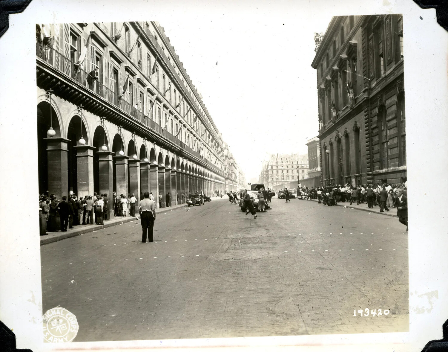 U.S. Army Signal Corps Photograph No. 193420 — Parisians Take Cover on a Flag-Draped Boulevard, Liberation of Paris, August 1944