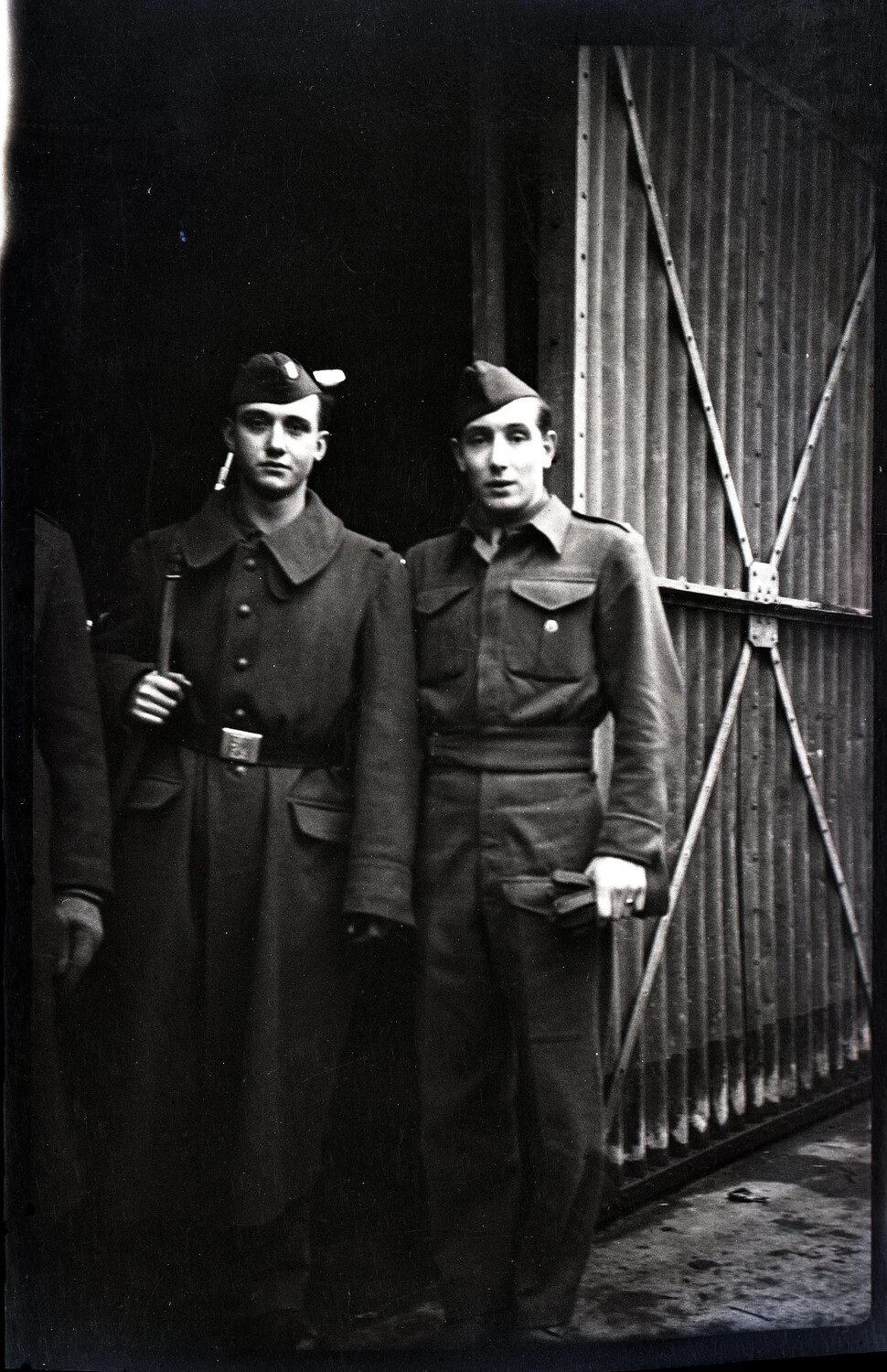 Two Young Men in Military-Style Uniform Before a Warehouse Door, Germany, WWII Era