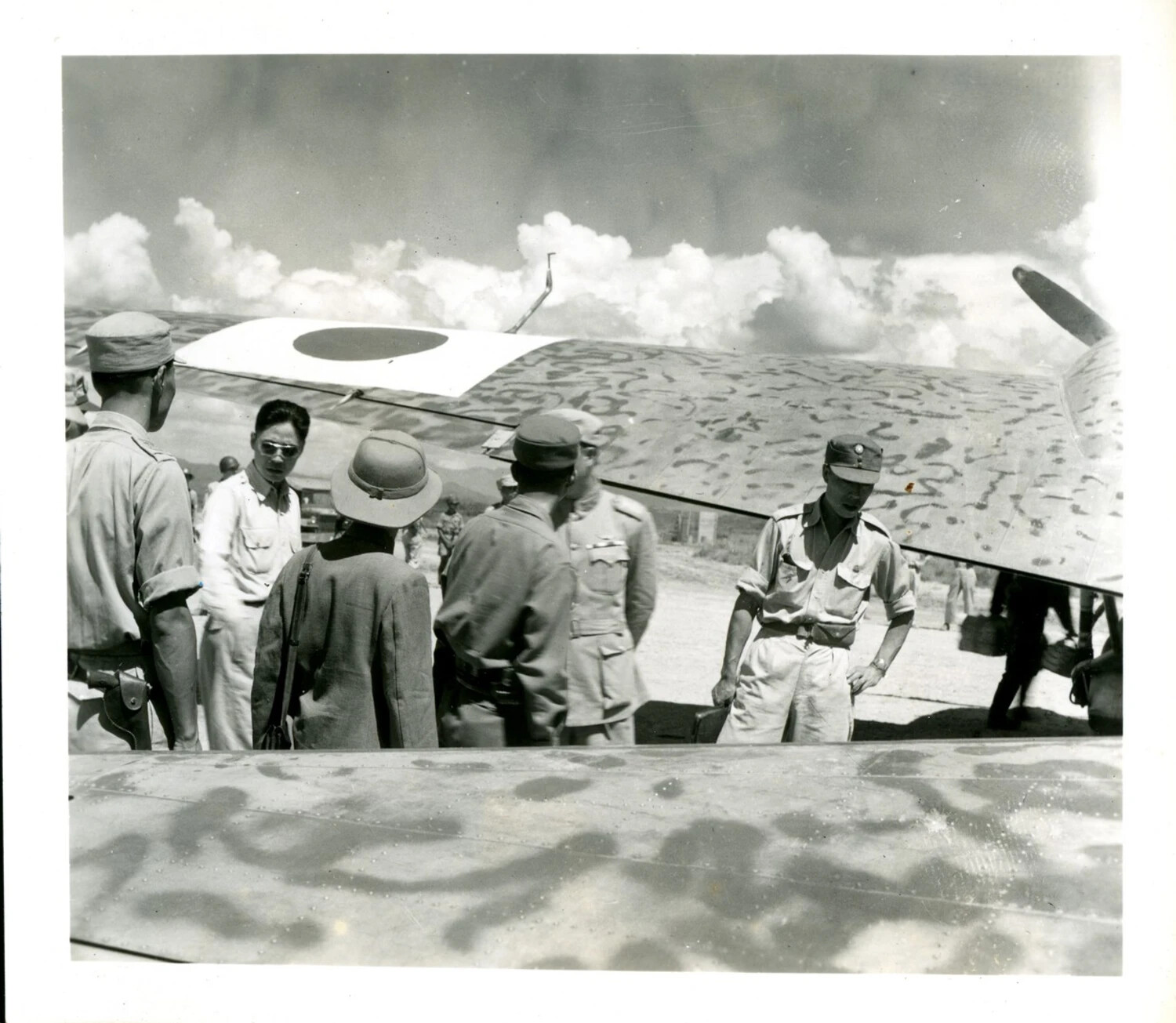 Group of Japanese Military and Civilian Personnel Beside a Camouflaged Aircraft, CBI Theater, WWII
