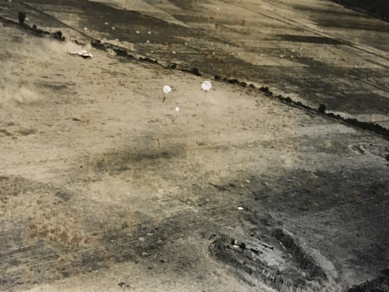Parafrag Bombs Descending Near Camouflaged Aircraft Dispersal Area Along Tree Line