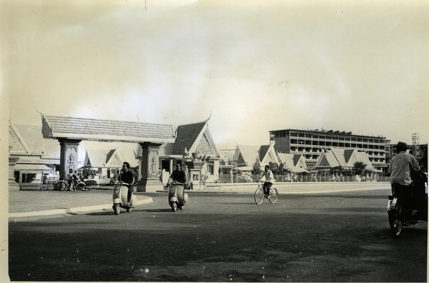 Street Scene with Scooters and Cyclo Before Traditional Khmer Gate, Hotel Cambodiana Under Construction, Phnom Penh (Vietnam-Cambodia Collection)