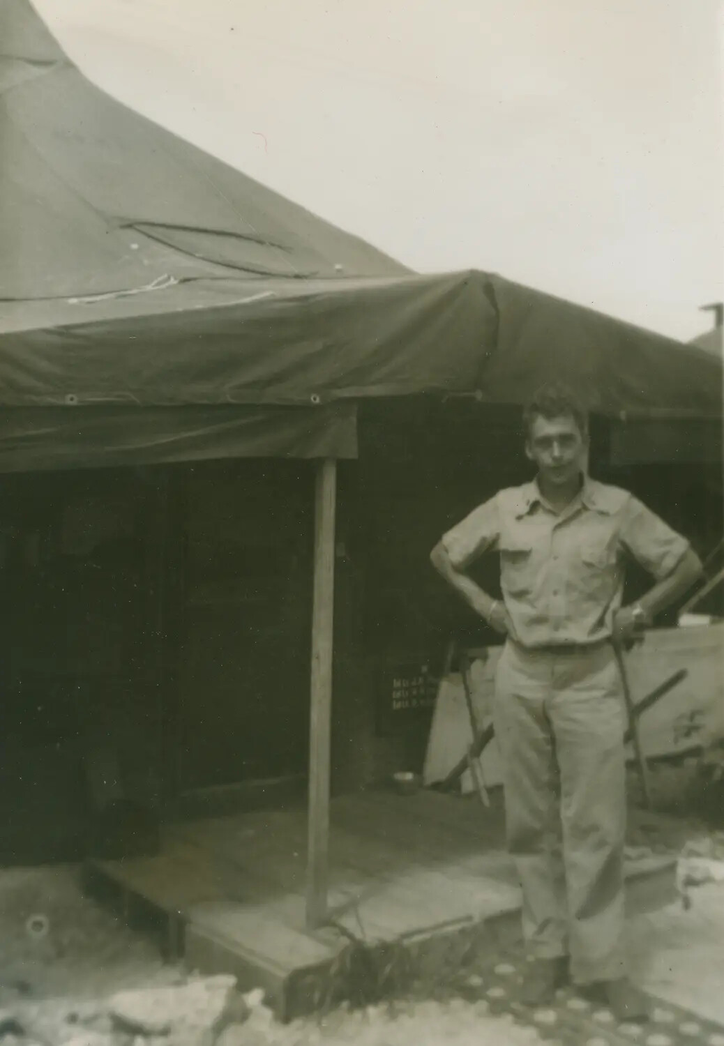 Serviceman Posing Outside Squad Tent with Wooden Deck, WWII Pacific Camp (McAleer Collection)