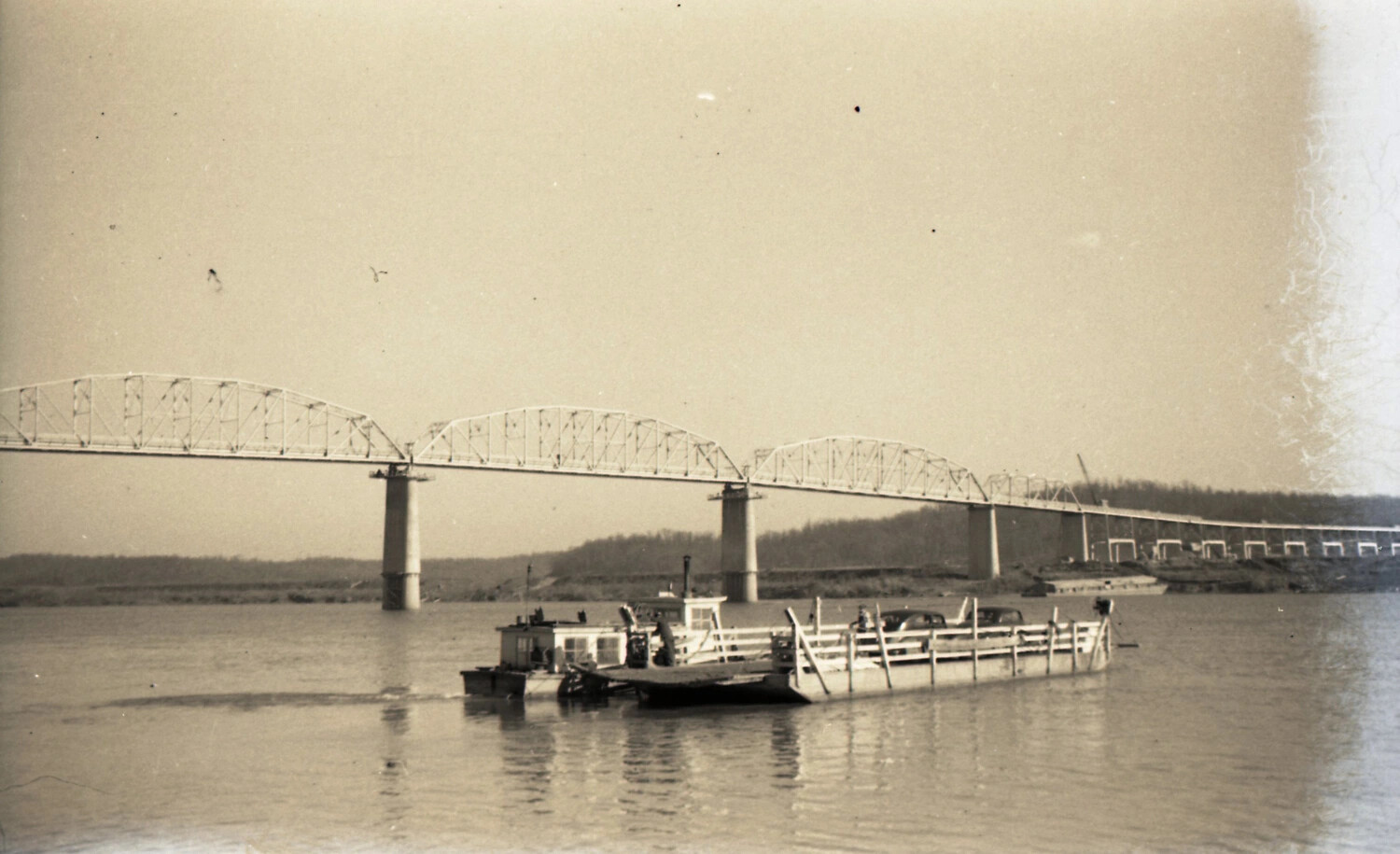 River Ferry Crossing Beneath Steel Arch Bridge
