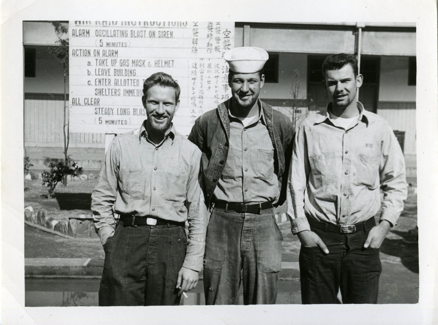 Three U.S. Servicemen in Front of Bilingual Air Raid Instructions Sign, Japan, Korean War Era