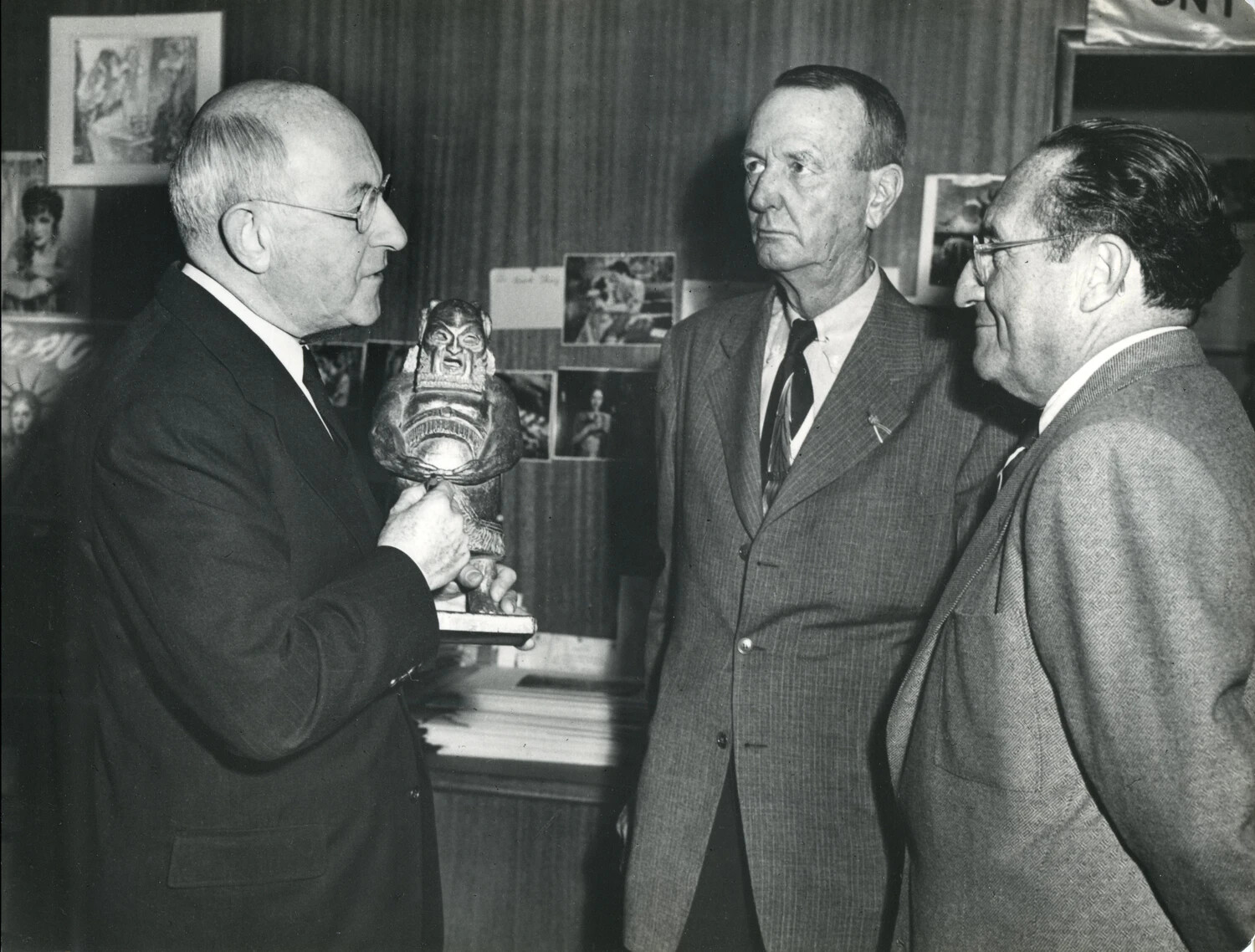 General Jonathan M. Wainwright Examining a Carved Statuette with Two Men, Studio Office Setting, 1949