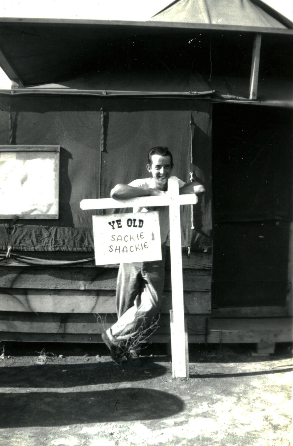 Marine Poses Beside Hand-Lettered 'Ye Old Sackie Shackie' Camp Sign, WWII