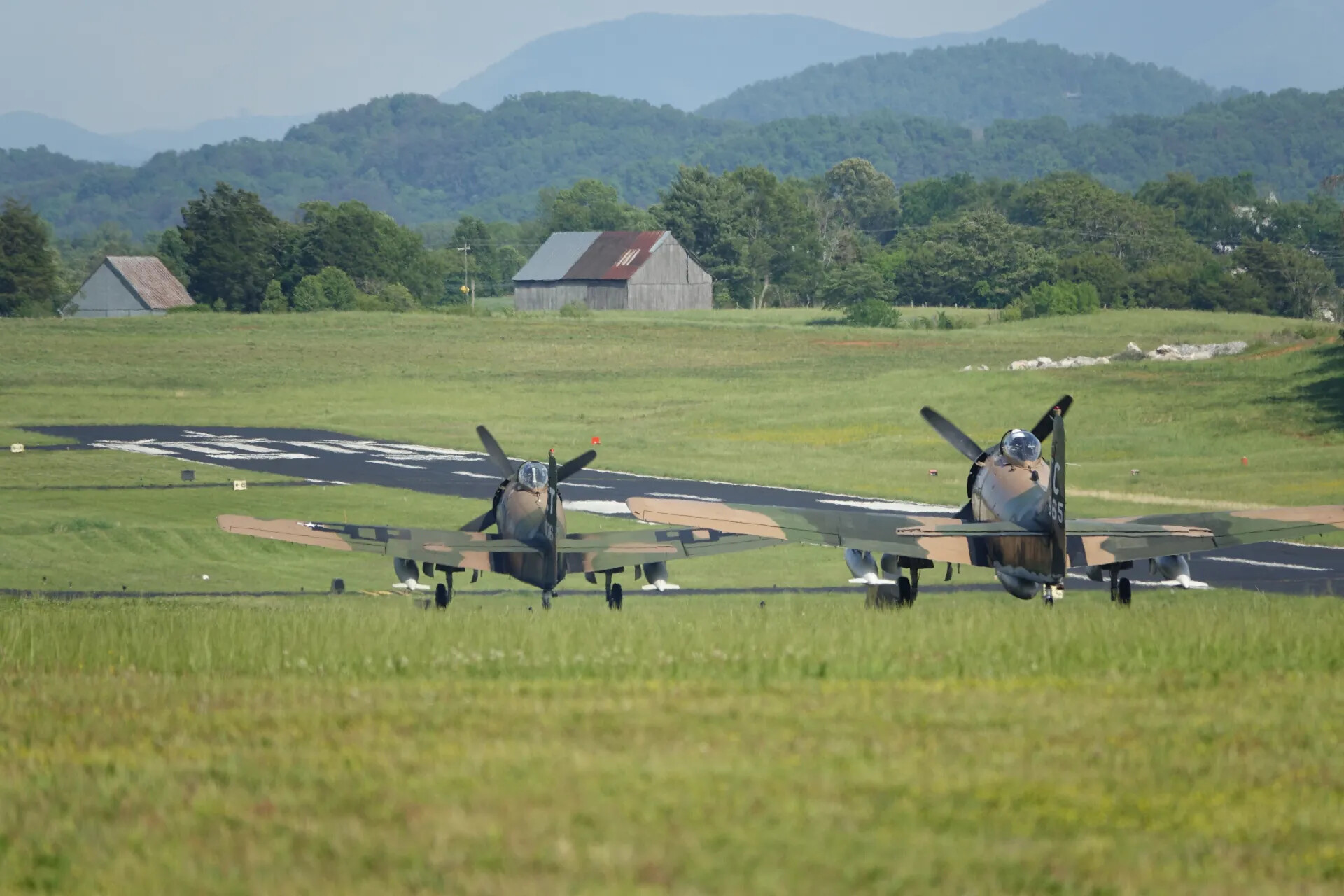 Two Camouflaged Douglas A-1 Skyraiders Taxiing with Mountain Backdrop, May 2019 Reunion Event