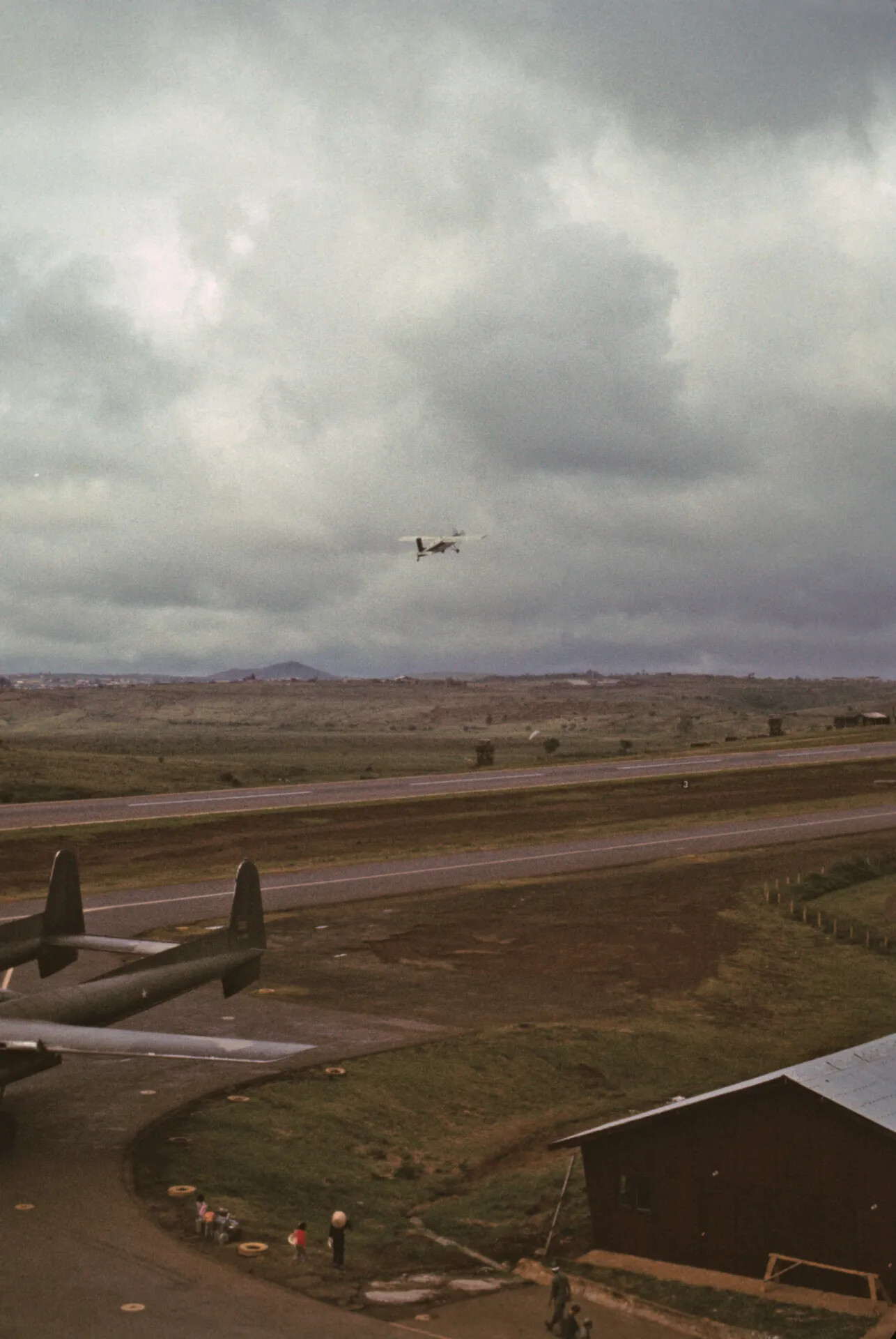 Small Aircraft Departing Under Storm Clouds Beside C-130 Hercules, Vietnam War Era