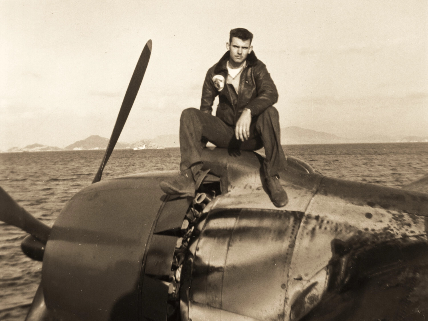 Naval Aviator Seated on Radial Engine Cowling of Single-Engine Fighter, Korean War Era