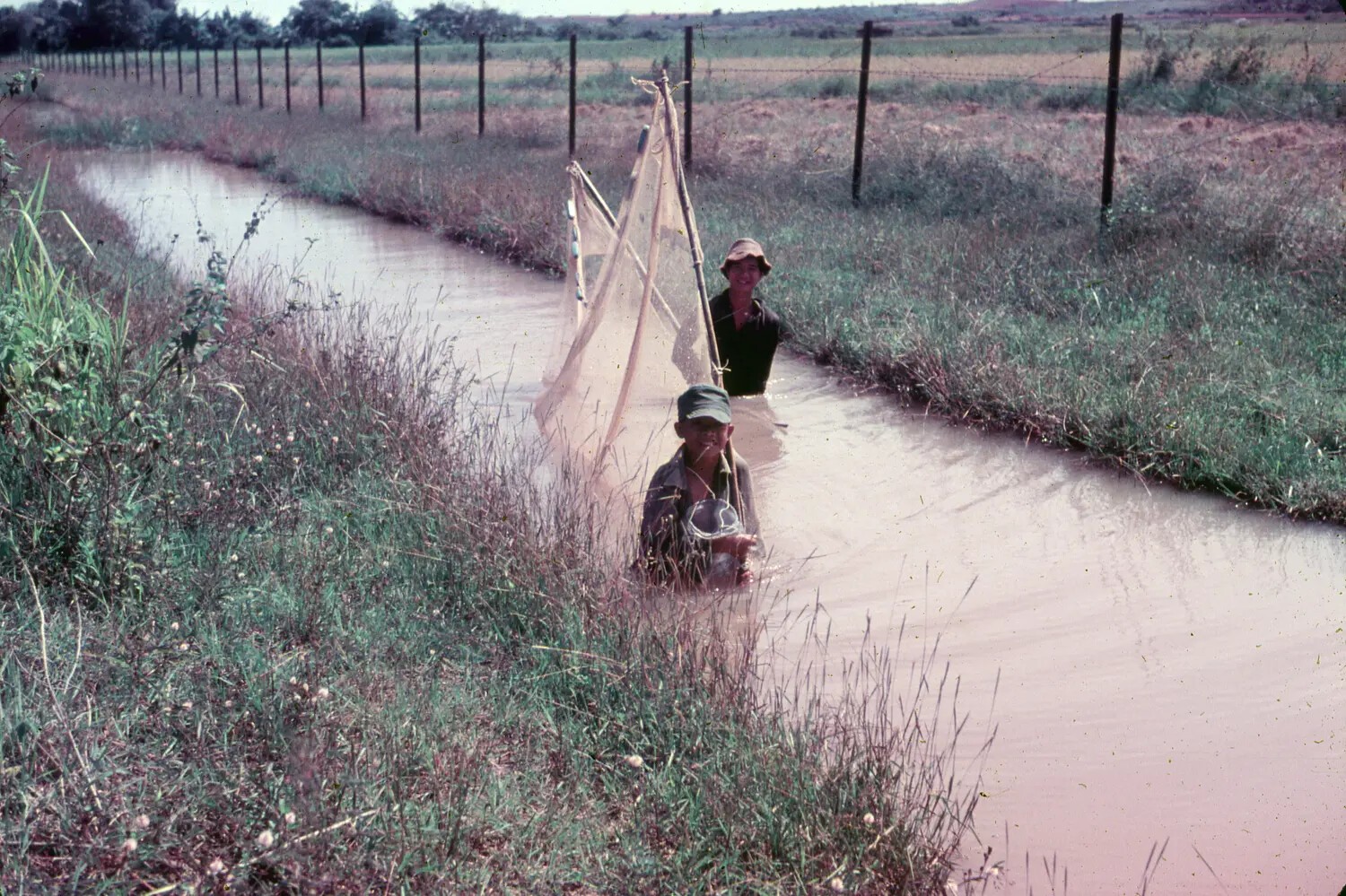Vietnamese Boys Fishing in Canal Near Air Base Perimeter Fence, 1965
