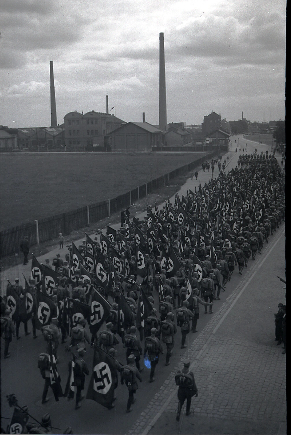 Mass Nazi Party March with Swastika Standards Through Industrial German Town, 1930s