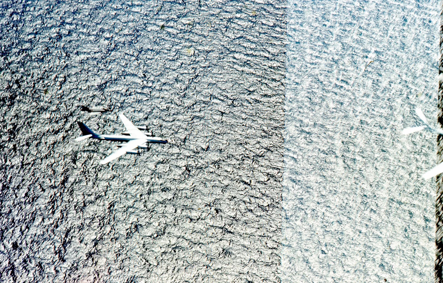 High-Altitude Aerial View of Four-Engine Jet Aircraft Over Cloud Deck, Vietnam War Era