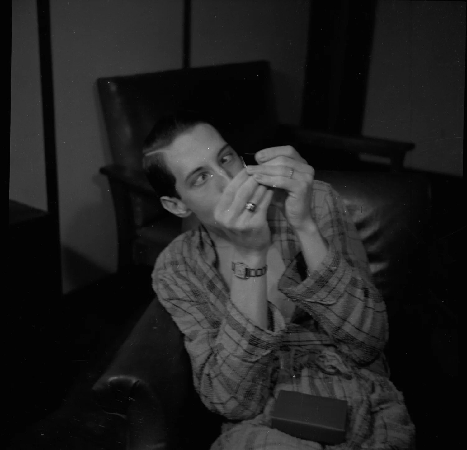 Young Man Lighting a Cigarette in Plaid Robe, Seated in Armchair - Candid Domestic Portrait