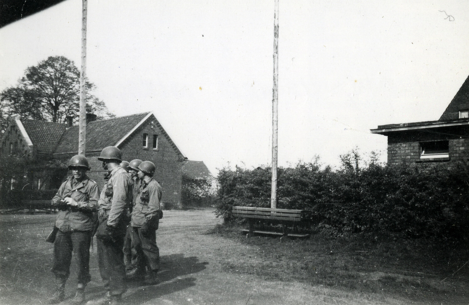 U.S. Soldiers Gathered Near Flagpoles at a Requisitioned German Farmstead