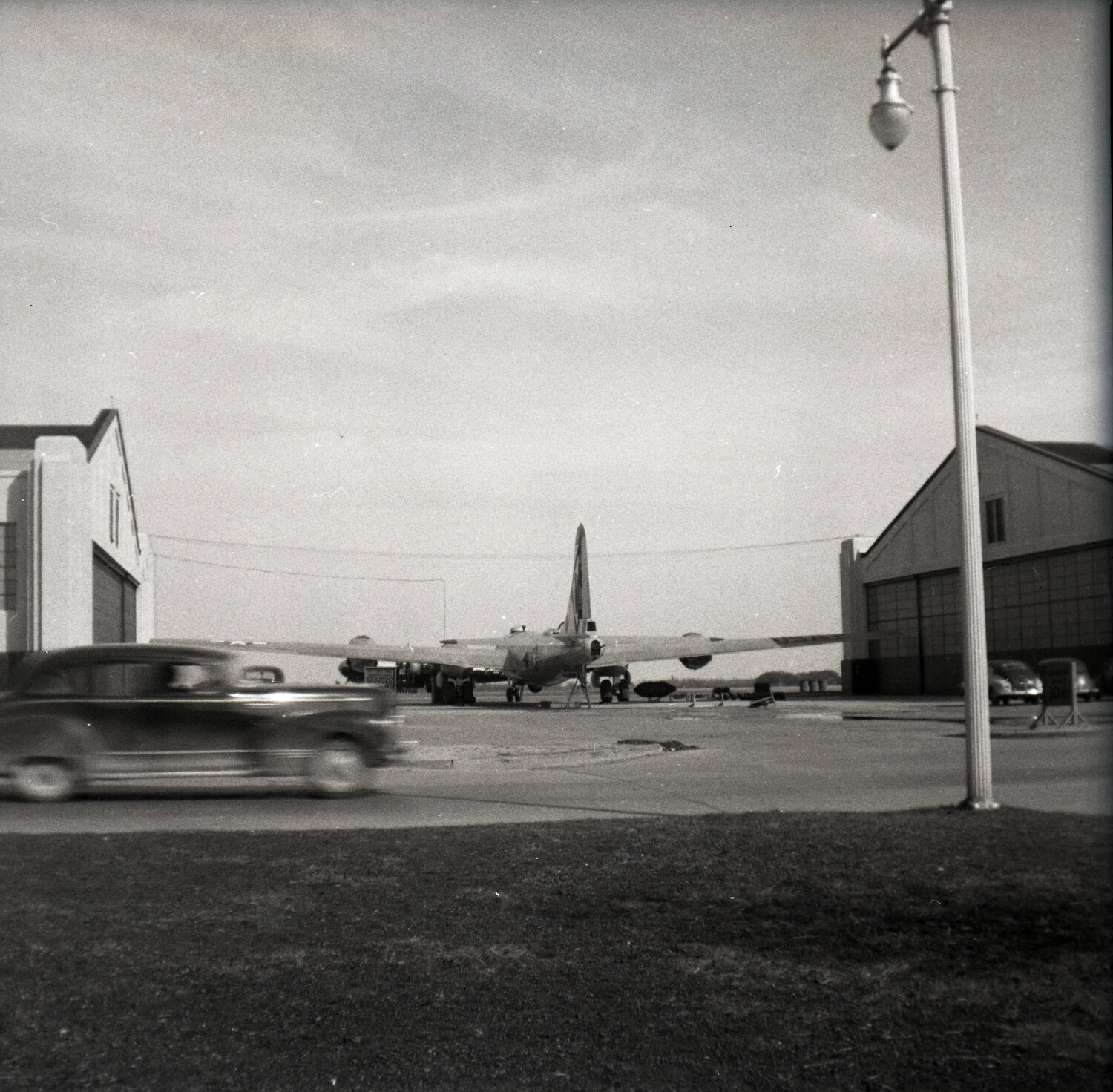 Twin-Engine Military Aircraft Parked Between Hangars, Airfield Access Road