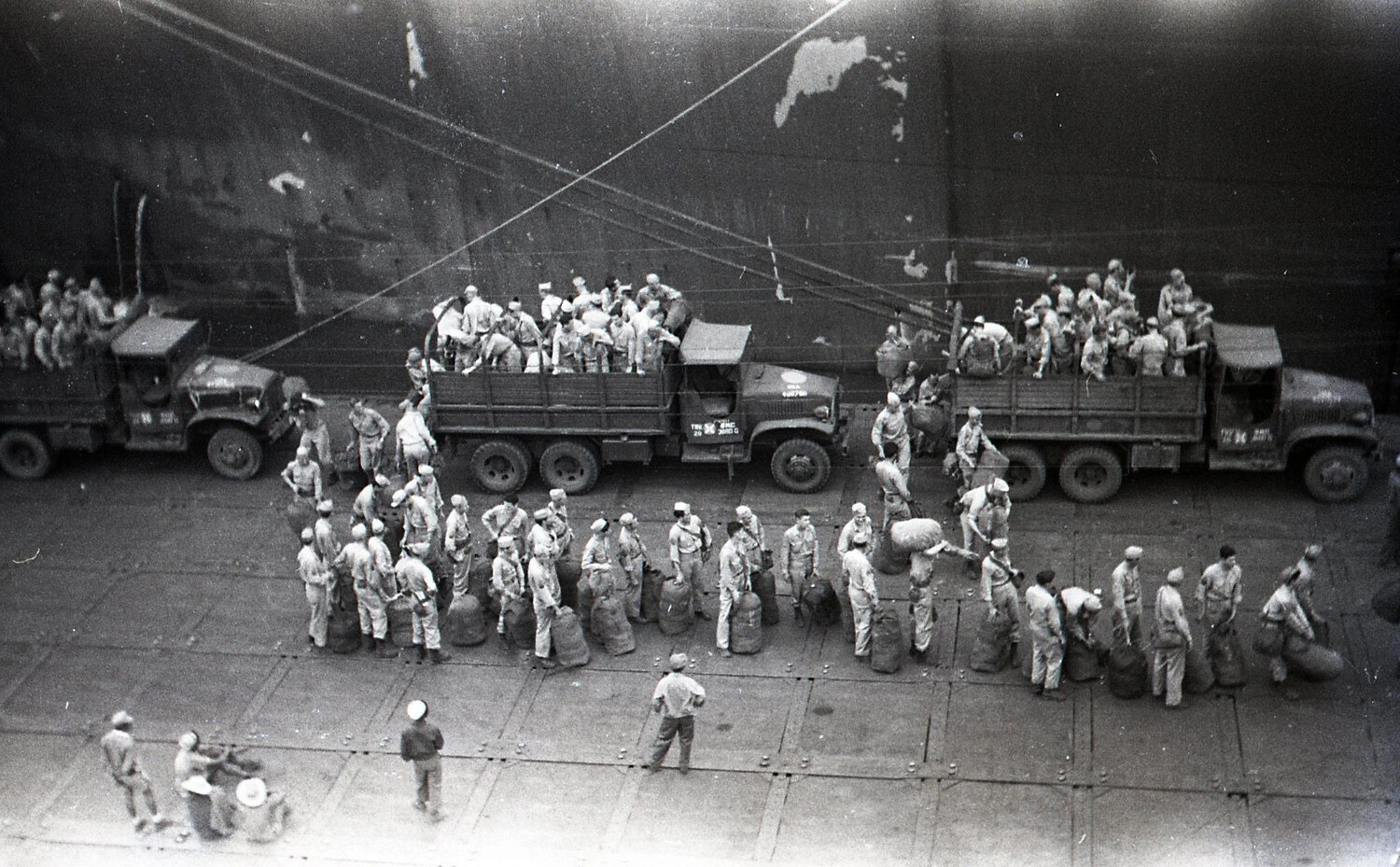 U.S. Army Troops and Duffel Bags Beside Transport Ship and Trucks at Philippine Pier, World War II
