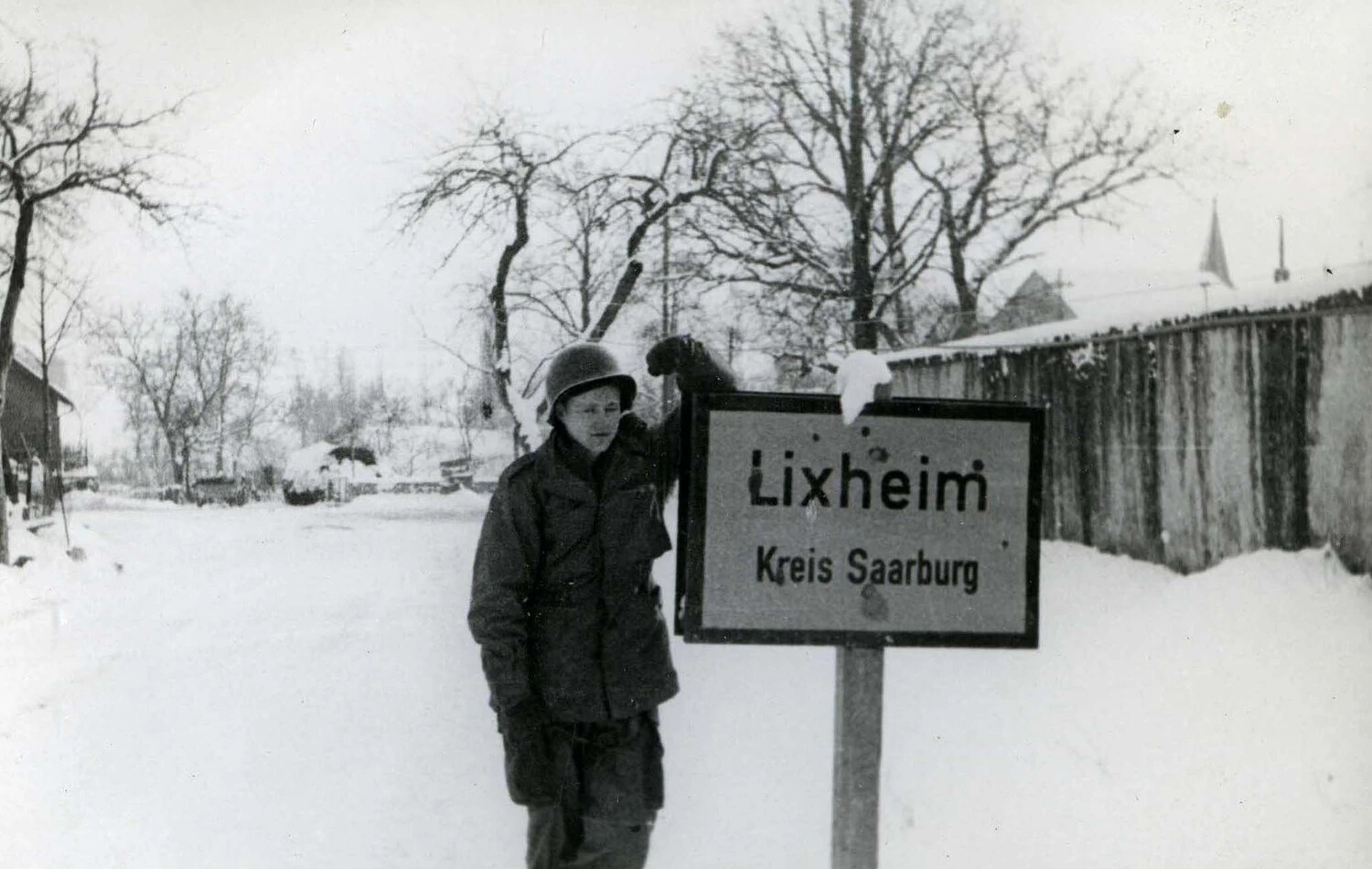 American Paratrooper Beside 'Lixheim, Kreis Saarburg' Sign in Winter, Alsace-Lorraine, 1944-1945