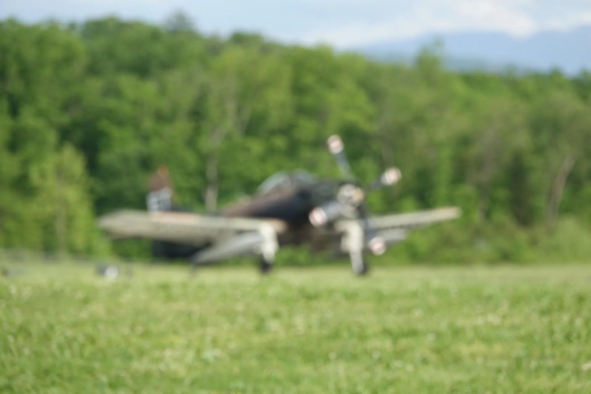 Out-of-Focus View of Dark-Painted WWII-Era Warbird on Grass Field, May 2019 Fly-In Event