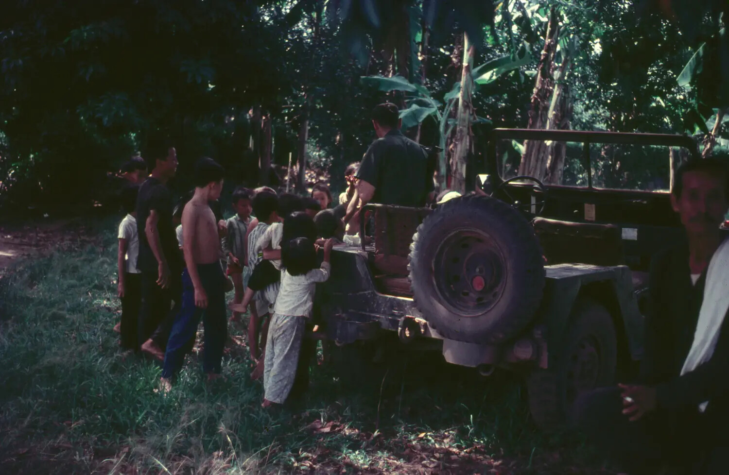 US Serviceman and Vietnamese Village Children Around Military Jeep, 1965