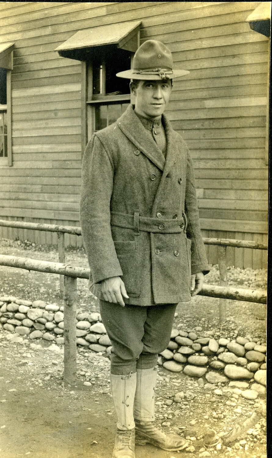 Soldier in Belted Wool Overcoat Outside a Camp Building, World War I Era