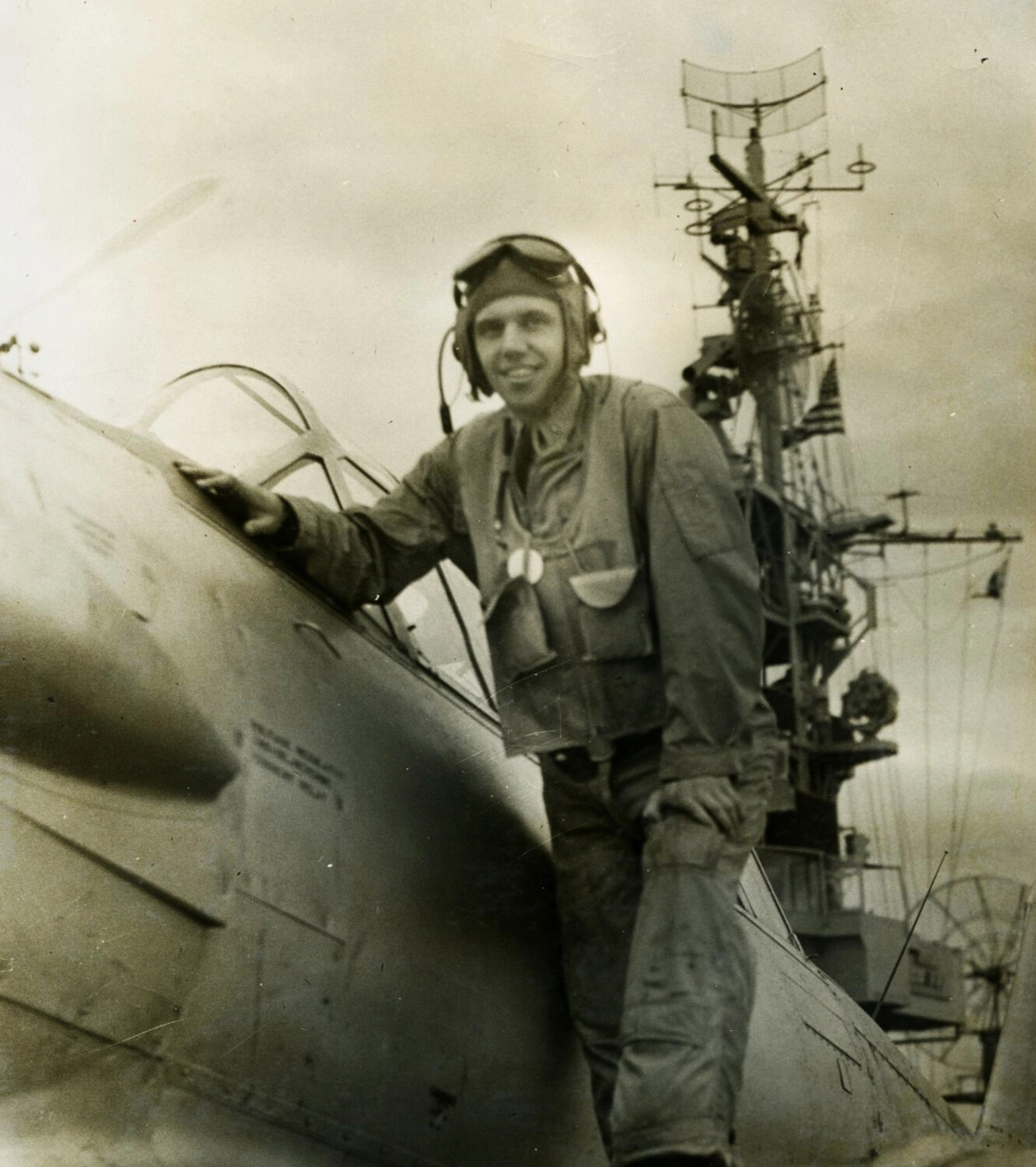 Naval Aviator on Wing of Fighter Aircraft with Warship Radar Mast in Background, Korean War Era